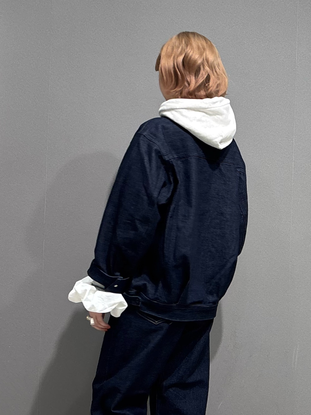 ブルー系のデニムパンツ、ベージュ系のパーカー、ブラック系のスニーカーを着用したレディースの冬コーディネートの5枚目の写真