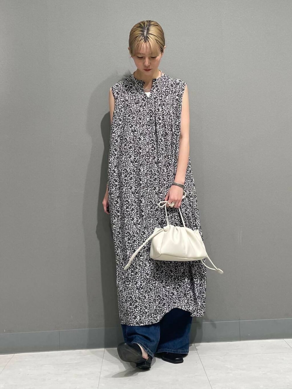 ホワイト系のショルダーバッグ、ブルー系のデニムパンツ、ブラック系のワンピースを着用したレディースの夏コーディネートの6枚目の写真