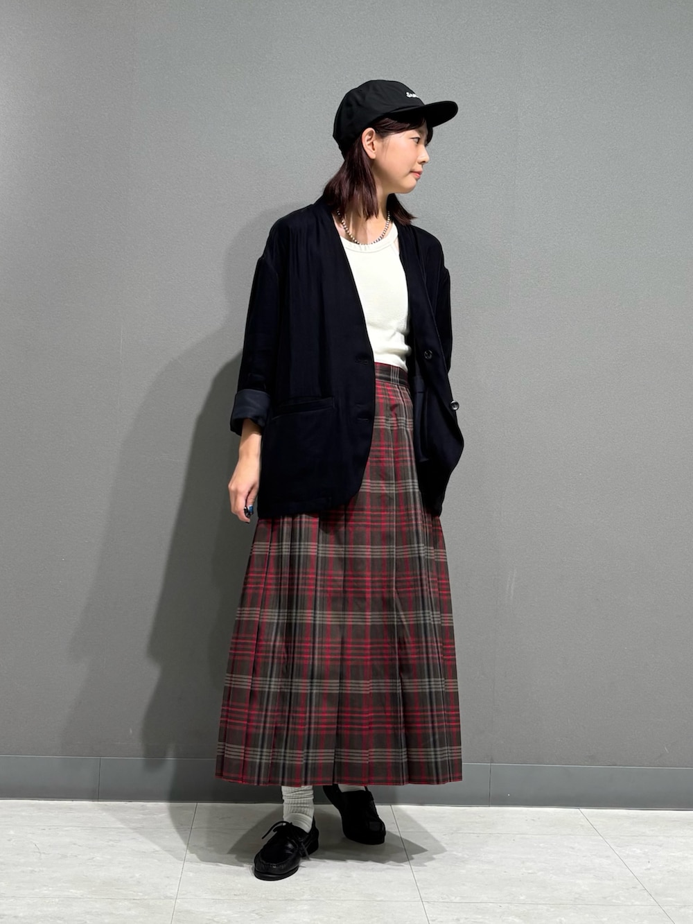 ブラウン系のスカート、ブラック系のノーカラージャケット、ブラック系のキャップを着用したレディースの秋コーディネートの2枚目の写真