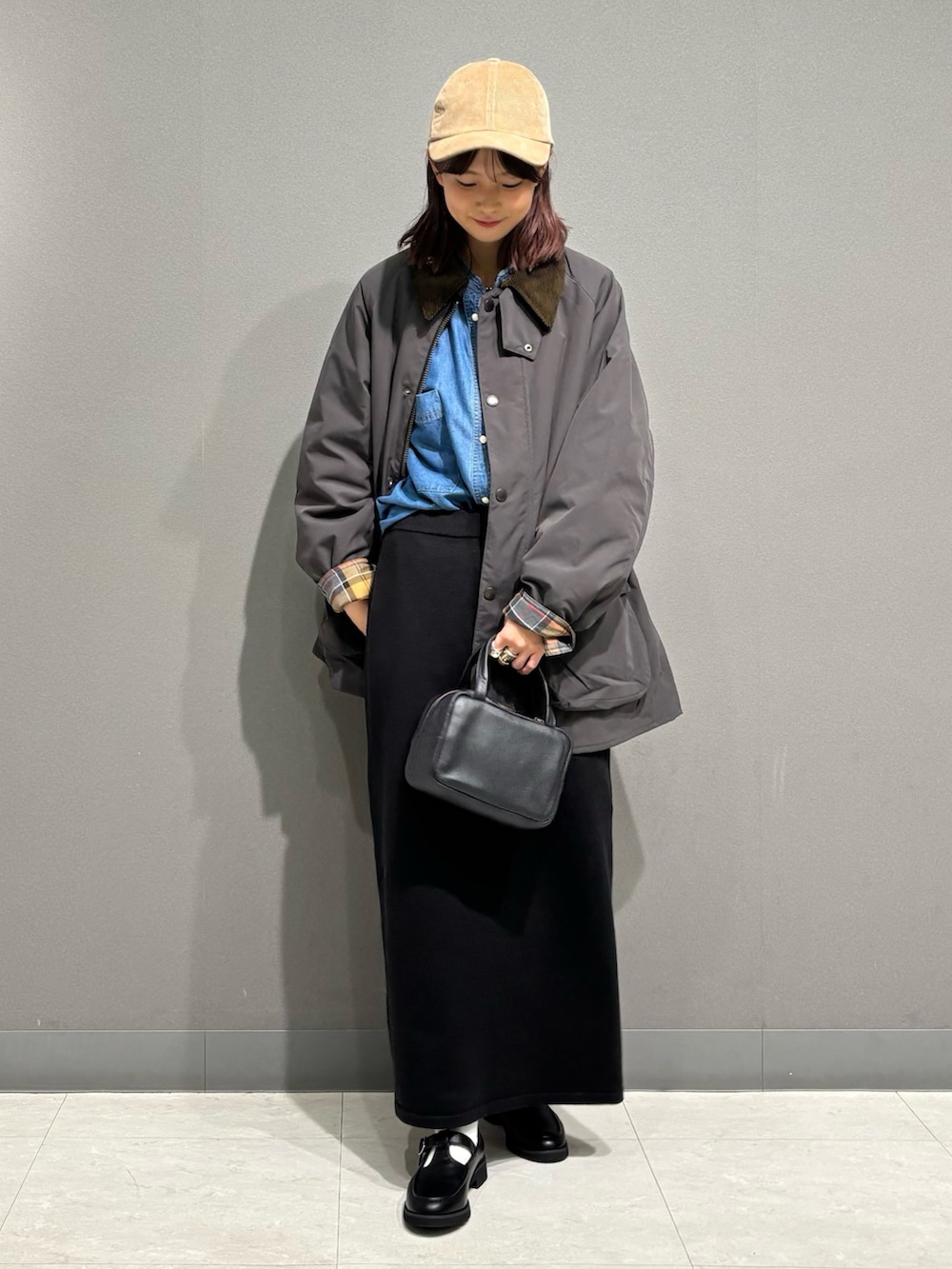 グレー系のその他アウター、ブラック系のローファー、ブラック系のスカートを着用したレディースの秋コーディネートの2枚目の写真