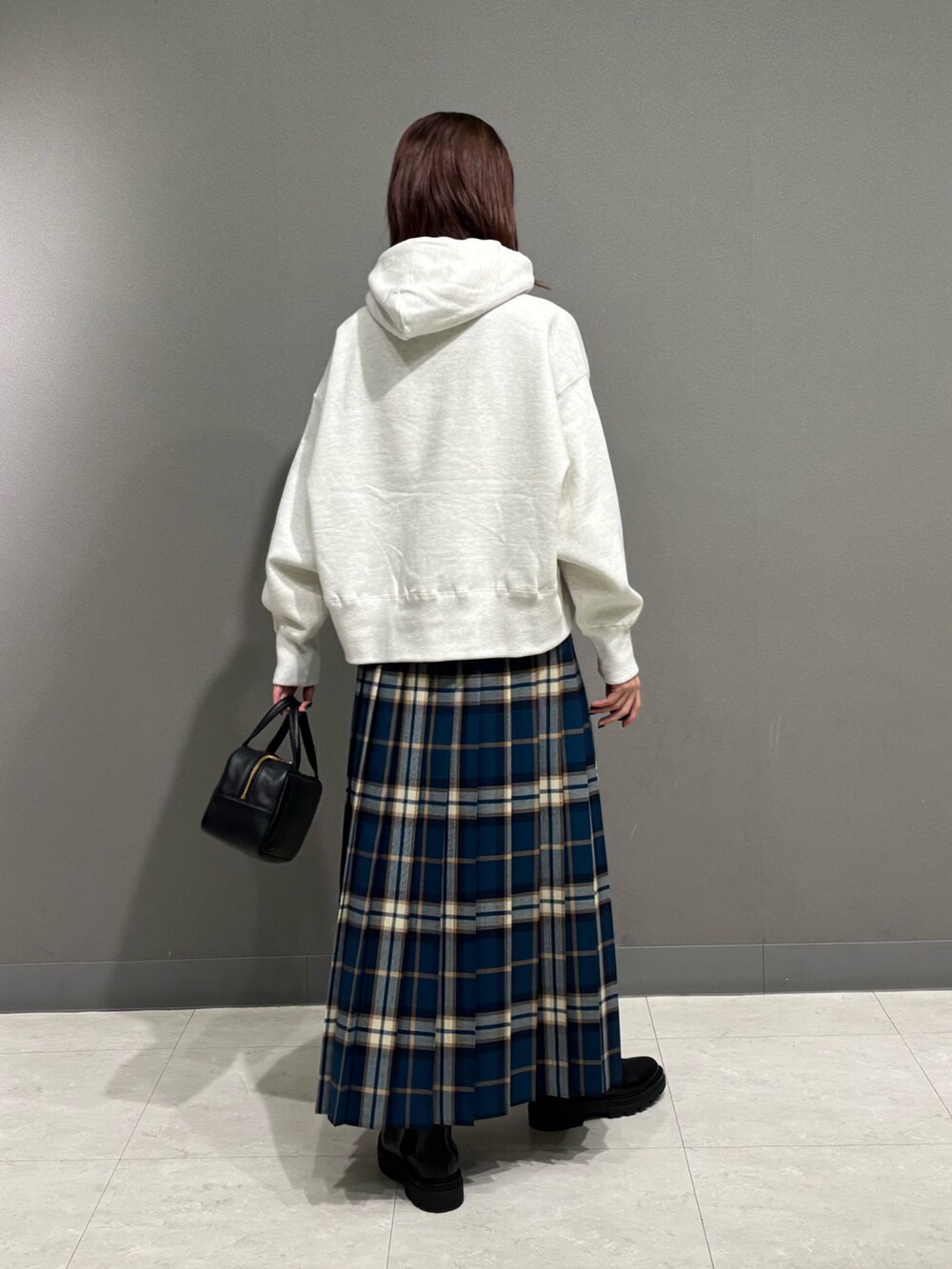 グリーン系のスカート、ブラック系のブーツ、ベージュ系のパーカーを着用したレディースの秋コーディネートの5枚目の写真