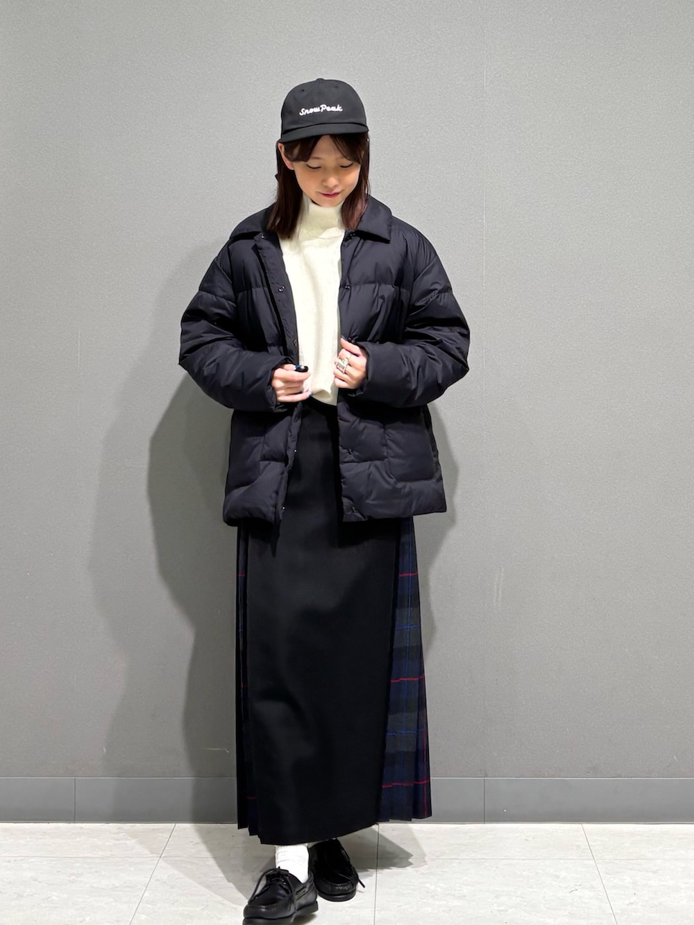 グレー系のスカート、ブラック系のダウンジャケット/コート、ベージュ系のスウェットを着用したレディースの秋コーディネートの2枚目の写真