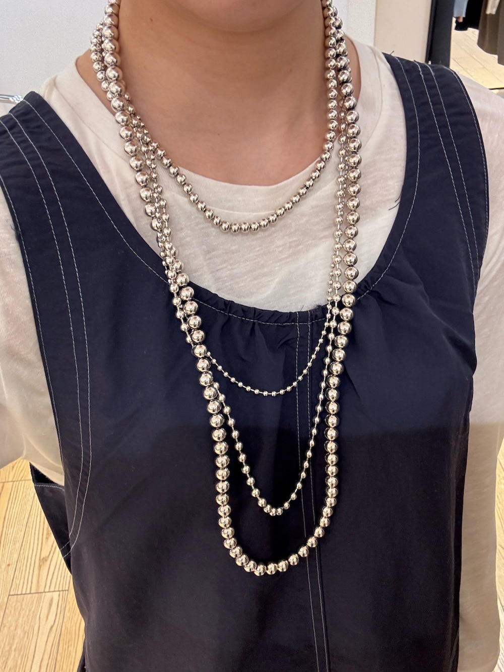 ブルー系のデニムパンツ、ブルー系のワンピース、ホワイト系のTシャツ/カットソーを着用したレディースの春コーディネートの3枚目の写真