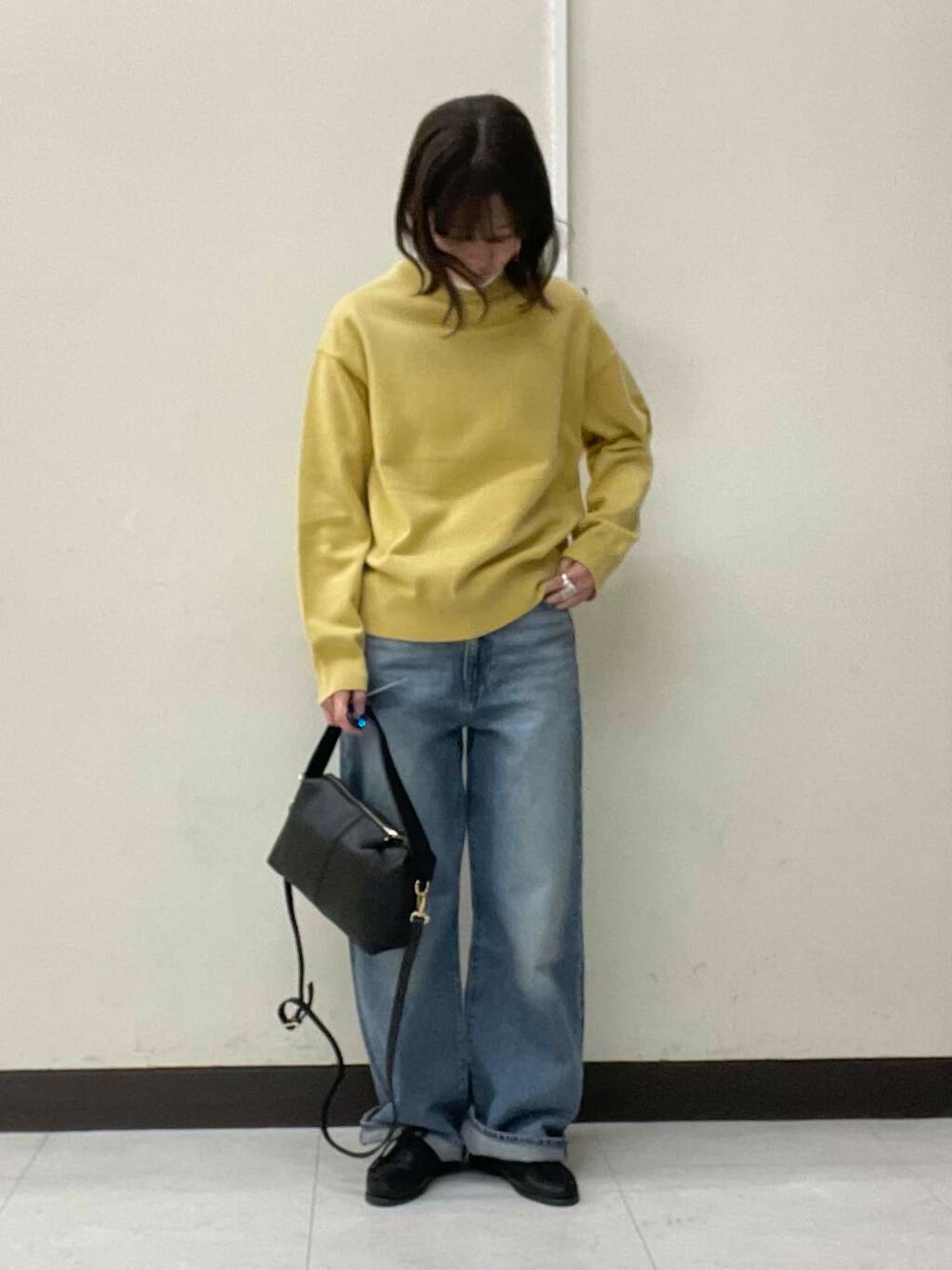 イエロー系のニット/セーター、ブルー系のデニムパンツ、ブラック系のショルダーバッグを着用したレディースの冬コーディネートの4枚目の写真
