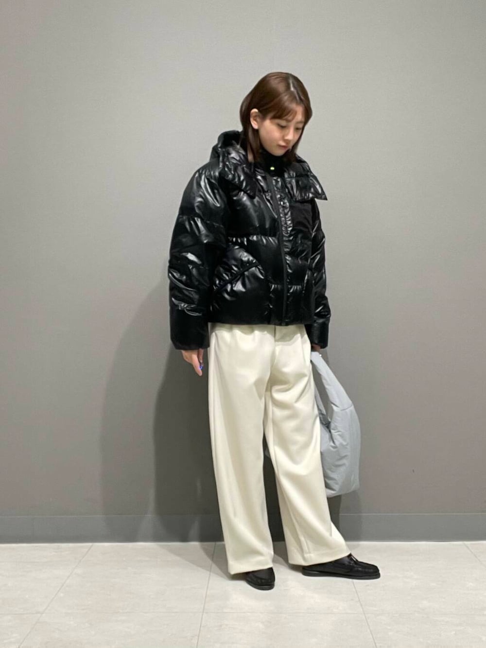 ホワイト系のその他パンツ、ブルー系のTシャツ/カットソー、ブラック系のダウンジャケット/コートを着用したレディースの冬コーディネートの3枚目の写真