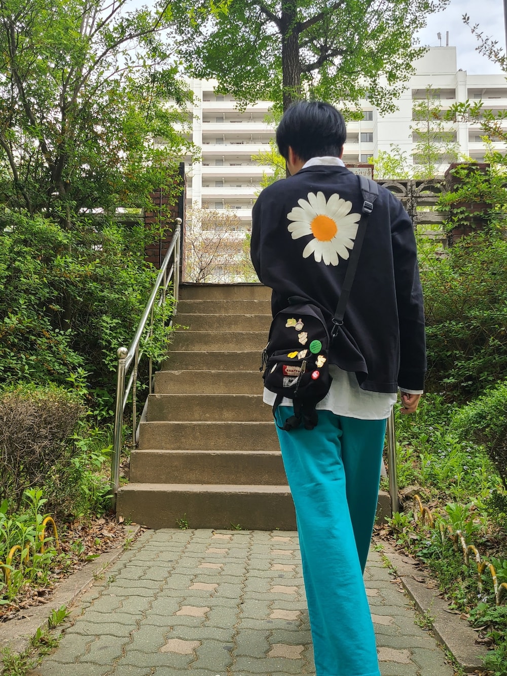 ブラック系のTシャツ/カットソー、ブラック系のバックパック/リュック、ブルー系のスウェットパンツを着用したメンズの春コーディネートの2枚目の写真