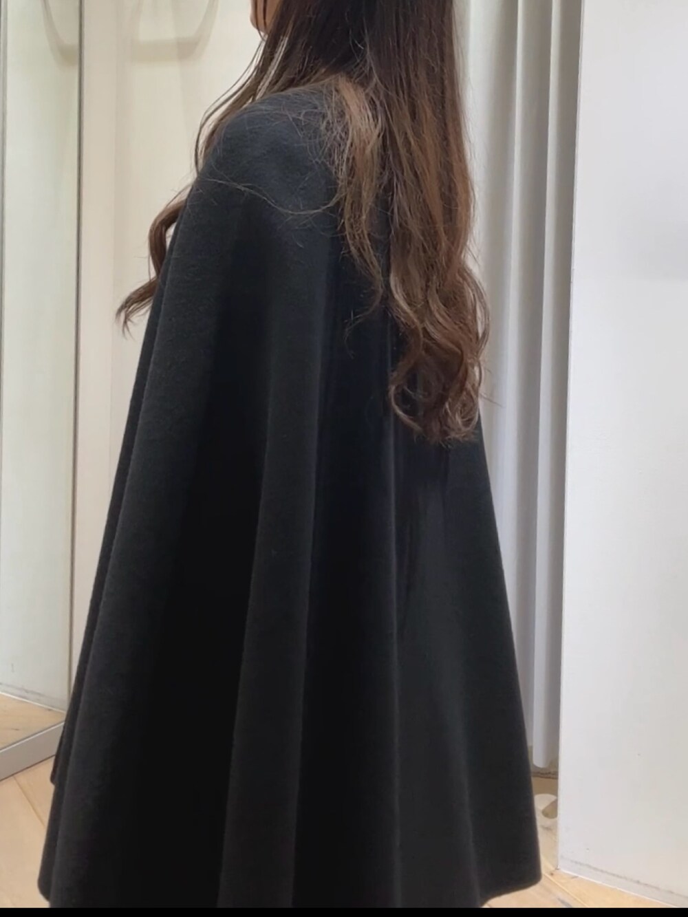 ブルー系のポンチョ、レッド系のニット/セーター、ベージュ系のトートバッグを着用したレディースの秋コーディネートの3枚目の写真