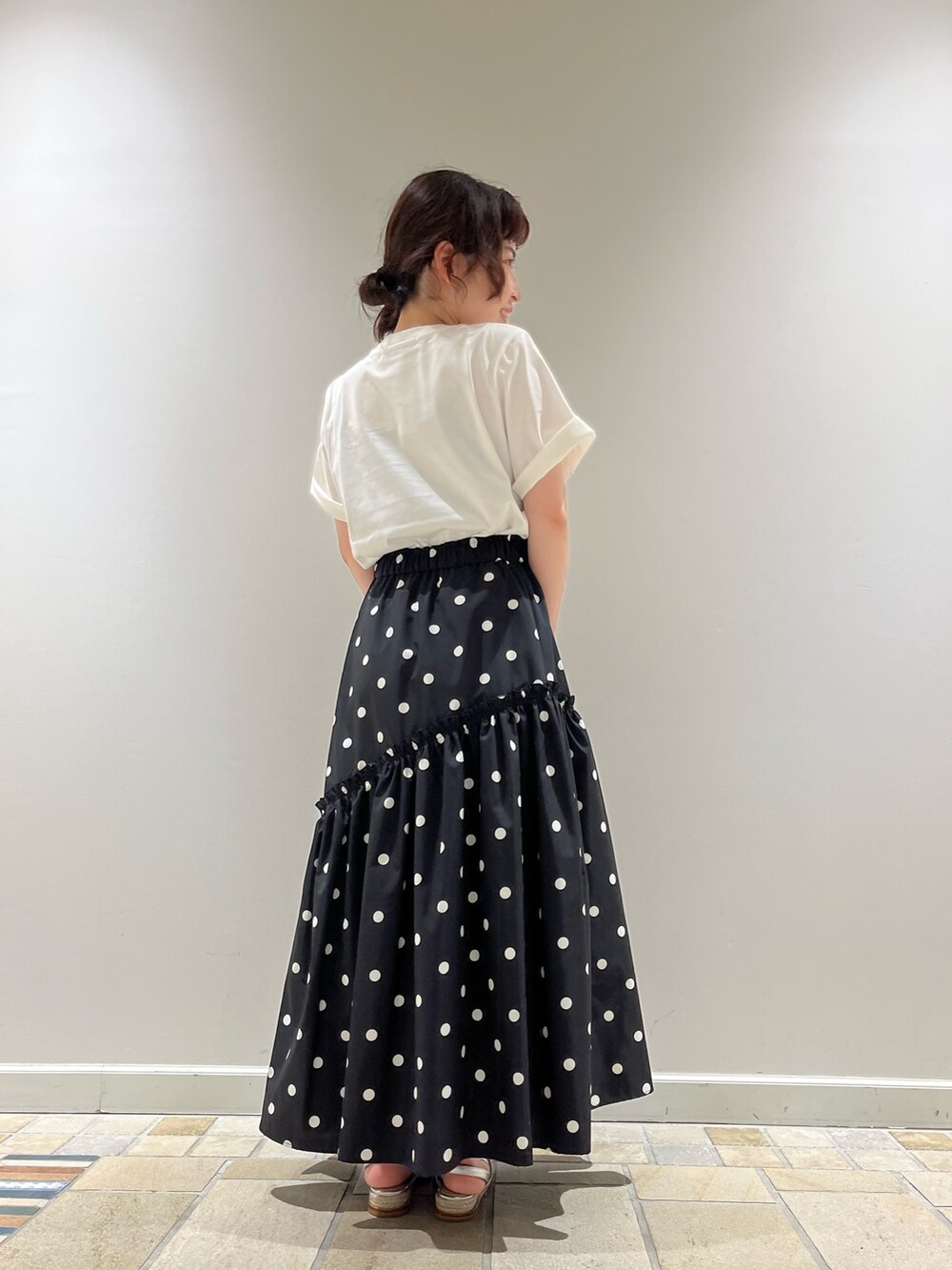 ブラック系のスカート、ホワイト系のTシャツ/カットソー、ブラック系のバッグを着用したレディースの春コーディネートの2枚目の写真