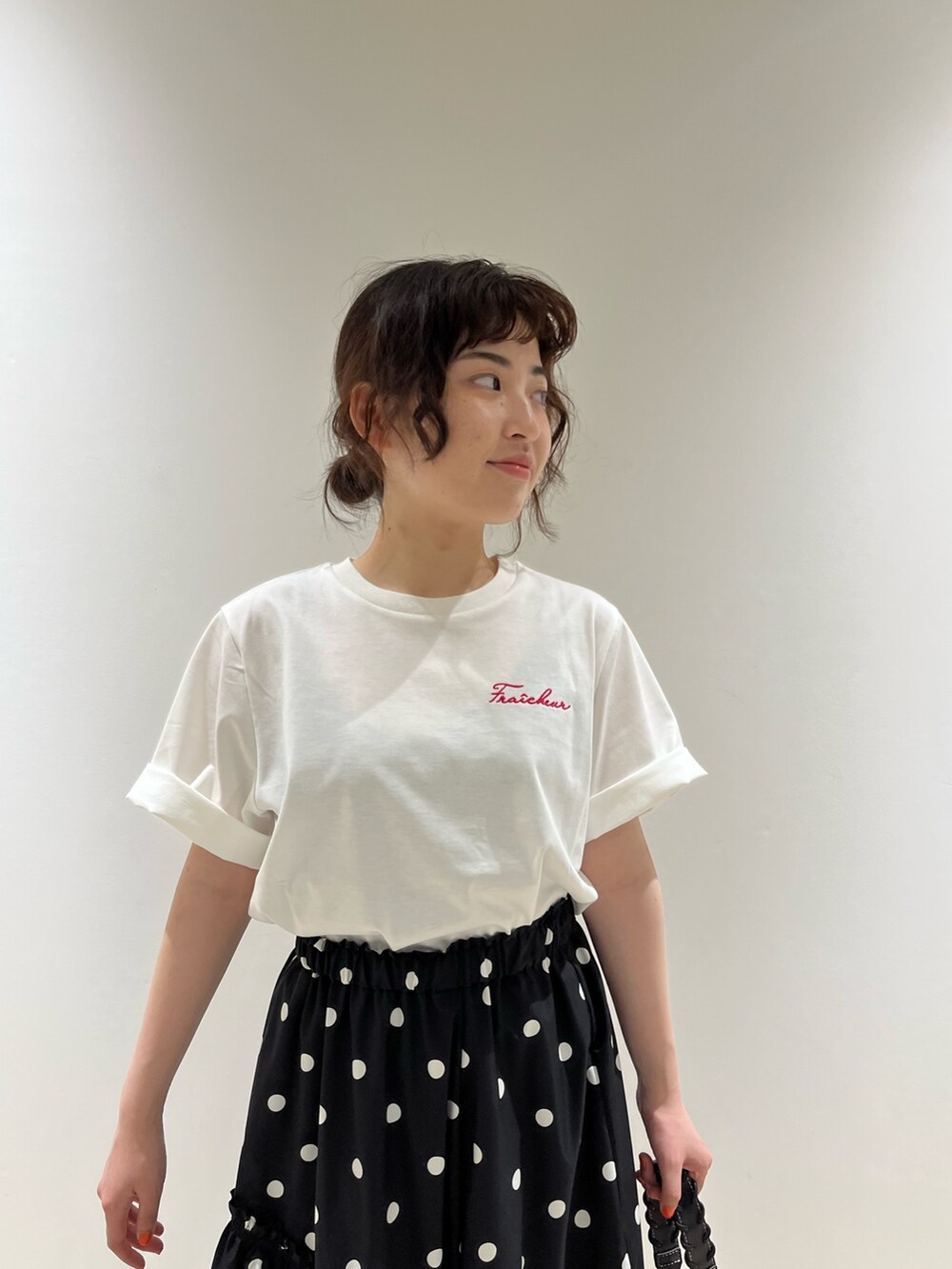 ブラック系のスカート、ホワイト系のTシャツ/カットソー、ブラック系のバッグを着用したレディースの春コーディネートの3枚目の写真