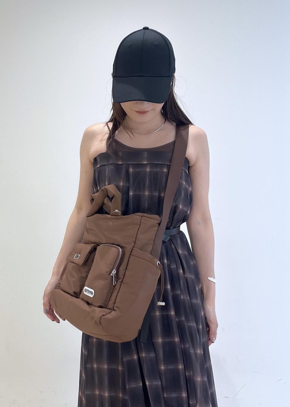 ブルー系のデニムパンツ、ブラウン系のスカート、ブラウン系のキャミソールを着用したレディースの夏コーディネートの5枚目の写真