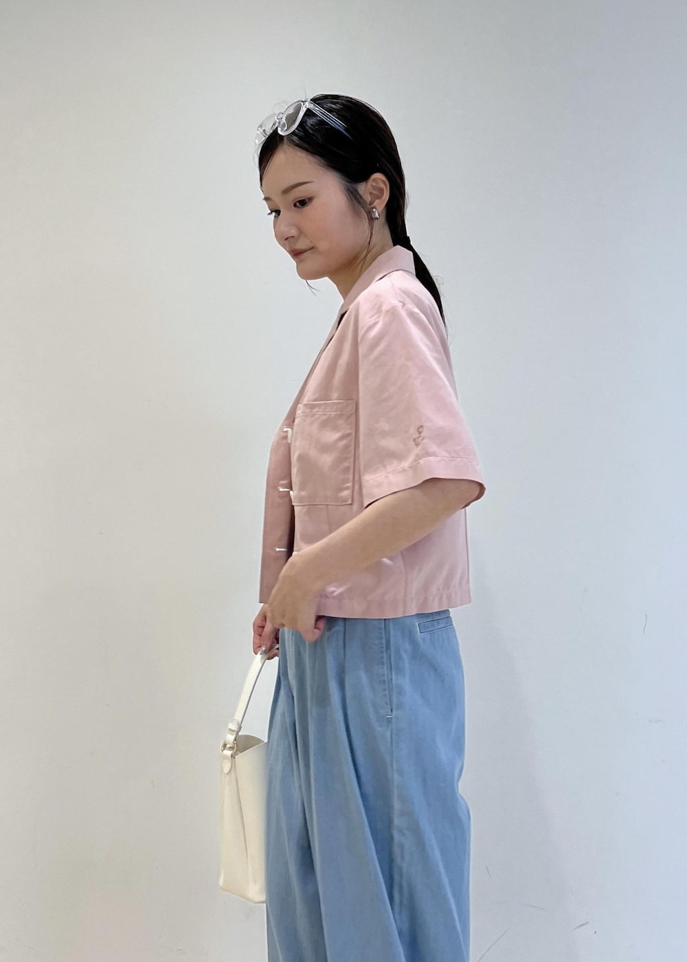 ホワイト系のショルダーバッグ、ホワイト系のサンダル、ブルー系のデニムパンツを着用したレディースの夏コーディネートの6枚目の写真