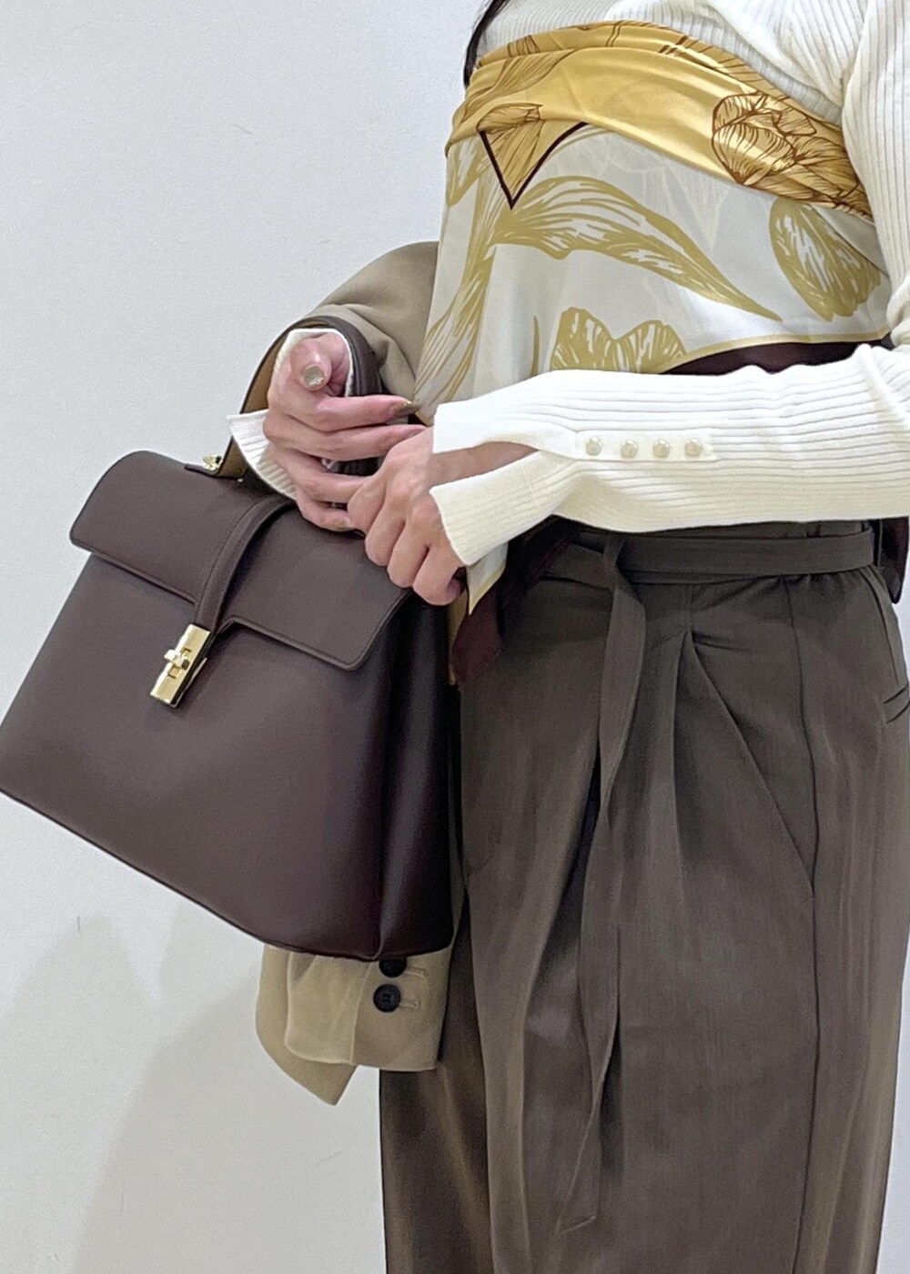 ブラウン系のハンドバッグ、ホワイト系のパンプス、ホワイト系のニット/セーターを着用したレディースの秋コーディネートの4枚目の写真