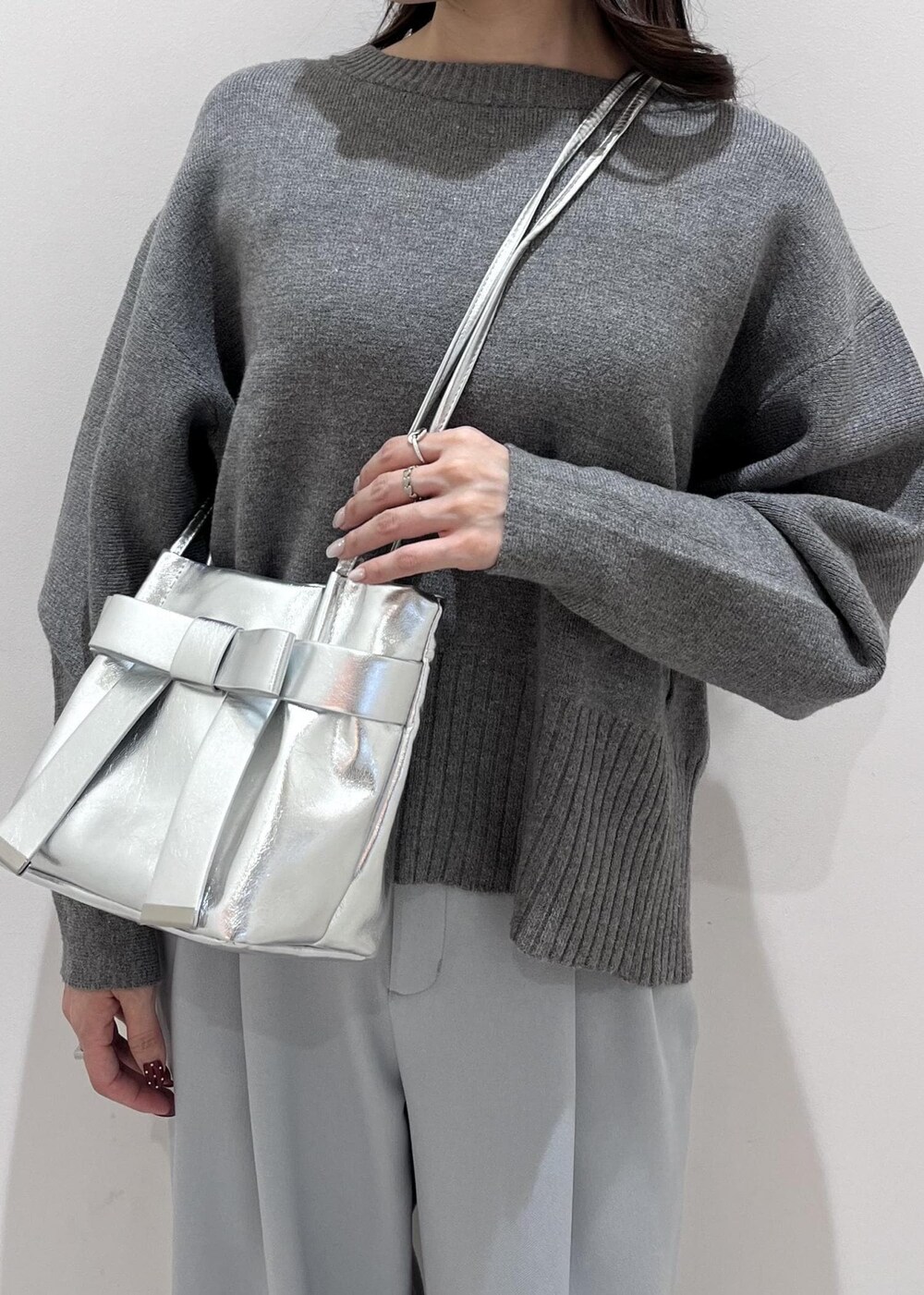 シルバー系のパンプス、シルバー系のショルダーバッグ、ブルー系のスラックスを着用したレディースの秋コーディネートの7枚目の写真