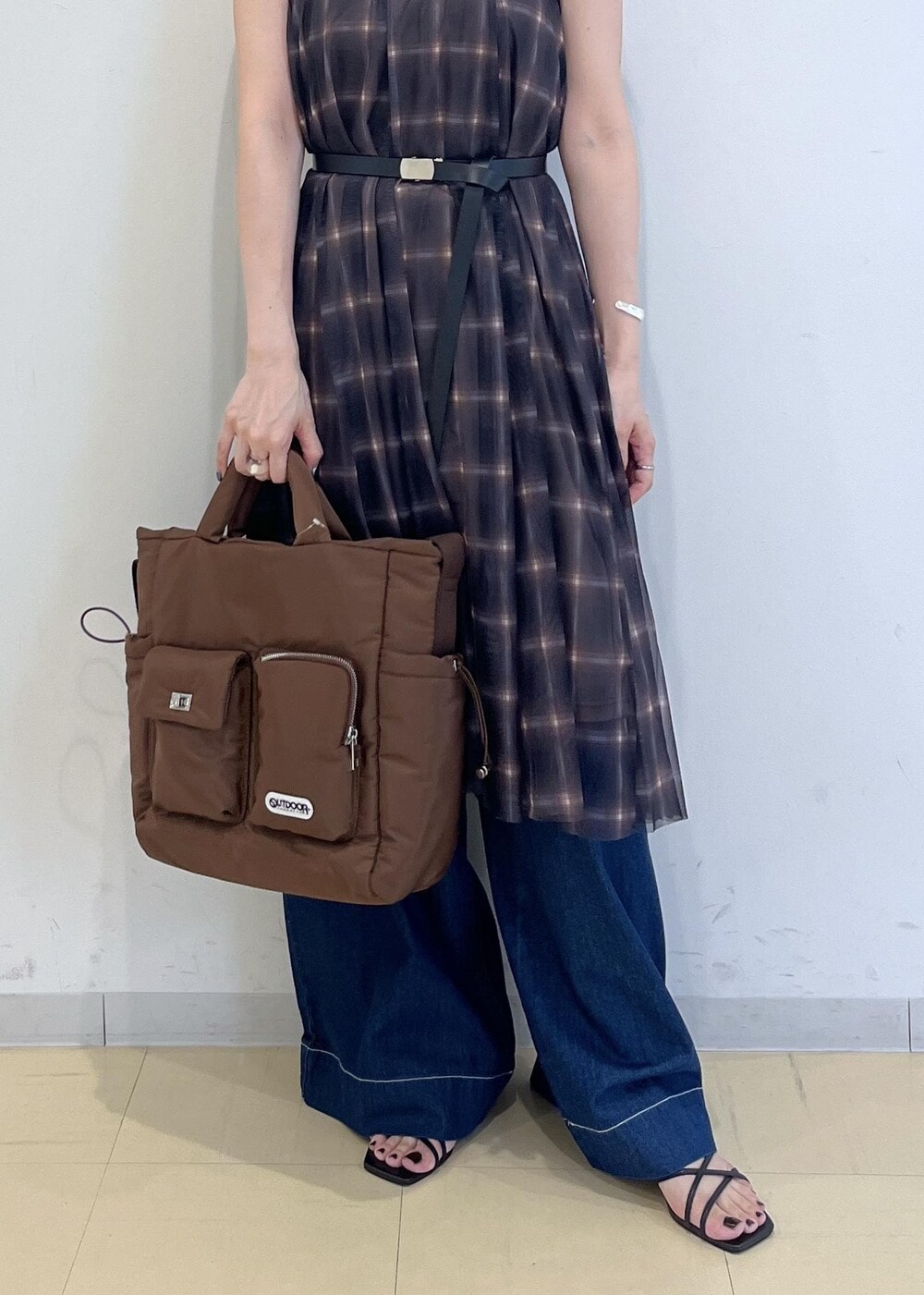 ブルー系のデニムパンツ、ブラウン系のスカート、ブラウン系のキャミソールを着用したレディースの夏コーディネートの4枚目の写真