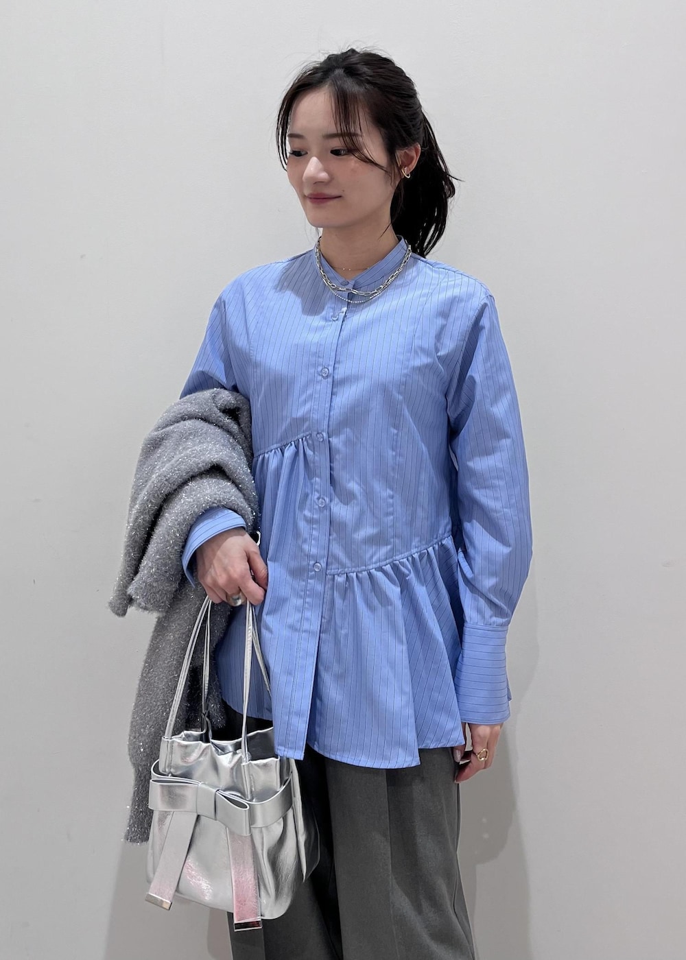 シルバー系のショルダーバッグ、シルバー系のブーツ、グレー系のスラックスを着用したレディースの冬コーディネートの4枚目の写真