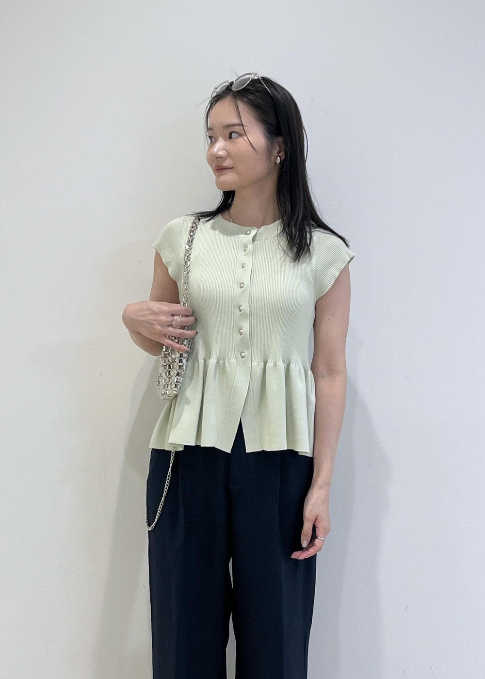 シルバー系のパンプス、シルバー系のハンドバッグ、ブルー系のスラックスを着用したレディースの夏コーディネートの8枚目の写真