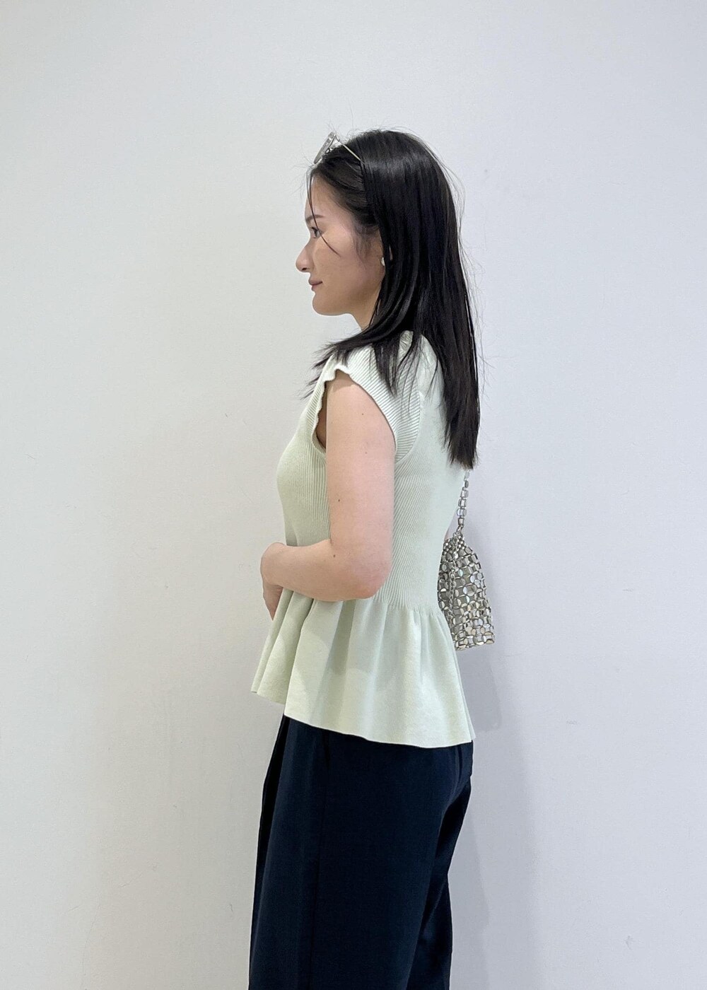 シルバー系のパンプス、シルバー系のハンドバッグ、ブルー系のスラックスを着用したレディースの夏コーディネートの7枚目の写真