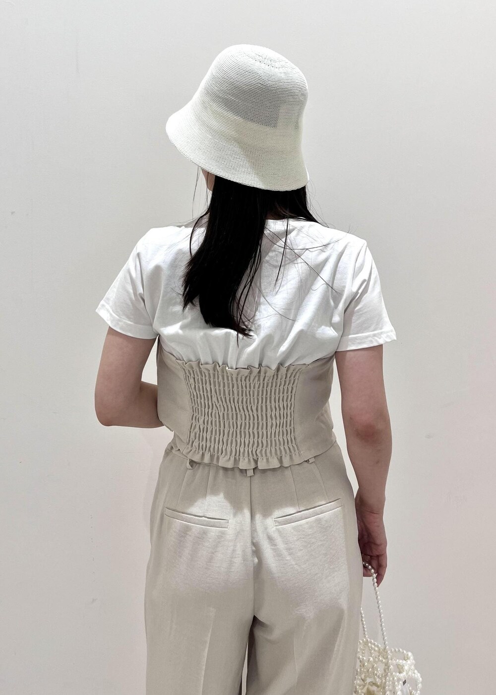 ホワイト系のサンダル、ホワイト系のスラックス、ホワイト系のハンドバッグを着用したレディースの夏コーディネートの4枚目の写真