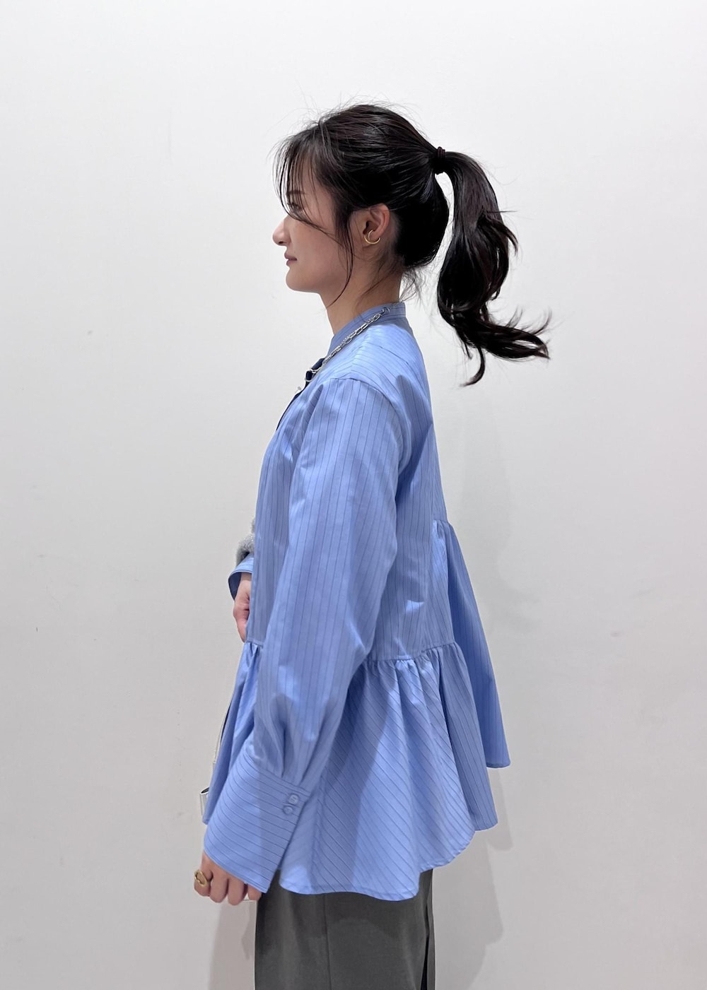 シルバー系のショルダーバッグ、シルバー系のブーツ、グレー系のスラックスを着用したレディースの冬コーディネートの5枚目の写真