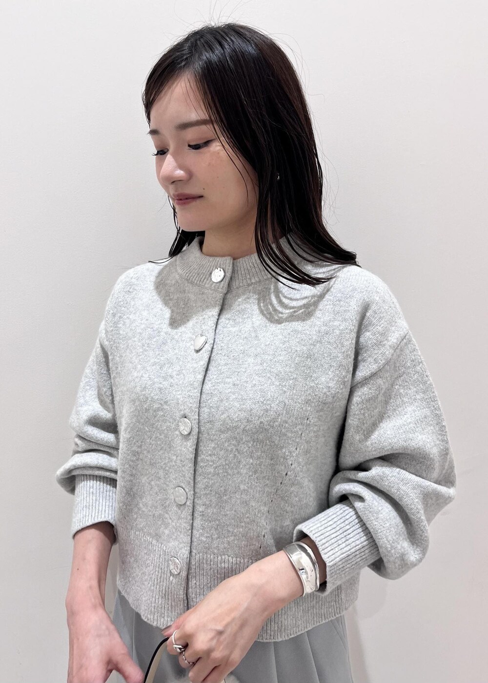 シルバー系のパンプス、ホワイト系のショルダーバッグ、グレー系のカーディガン/ボレロを着用したレディースの秋コーディネートの6枚目の写真