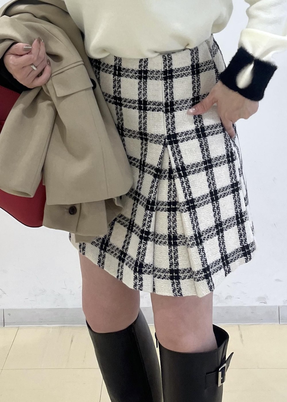 ブラック系のブーツ、ホワイト系のスカート、ホワイト系のニット/セーターを着用したレディースの冬コーディネートの6枚目の写真