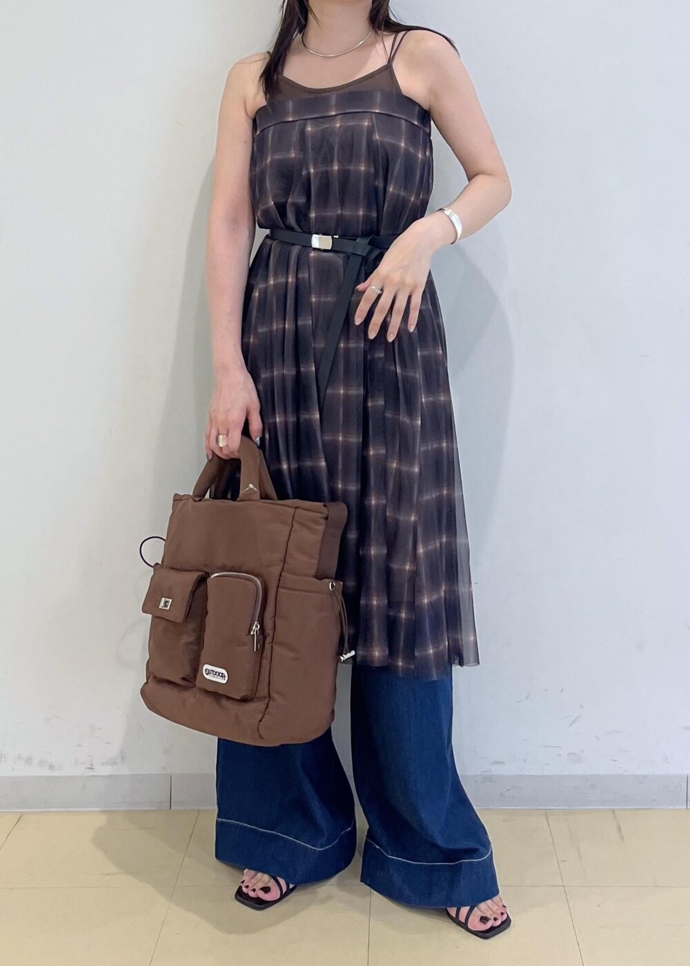 ブルー系のデニムパンツ、ブラウン系のスカート、ブラウン系のキャミソールを着用したレディースの夏コーディネートの2枚目の写真