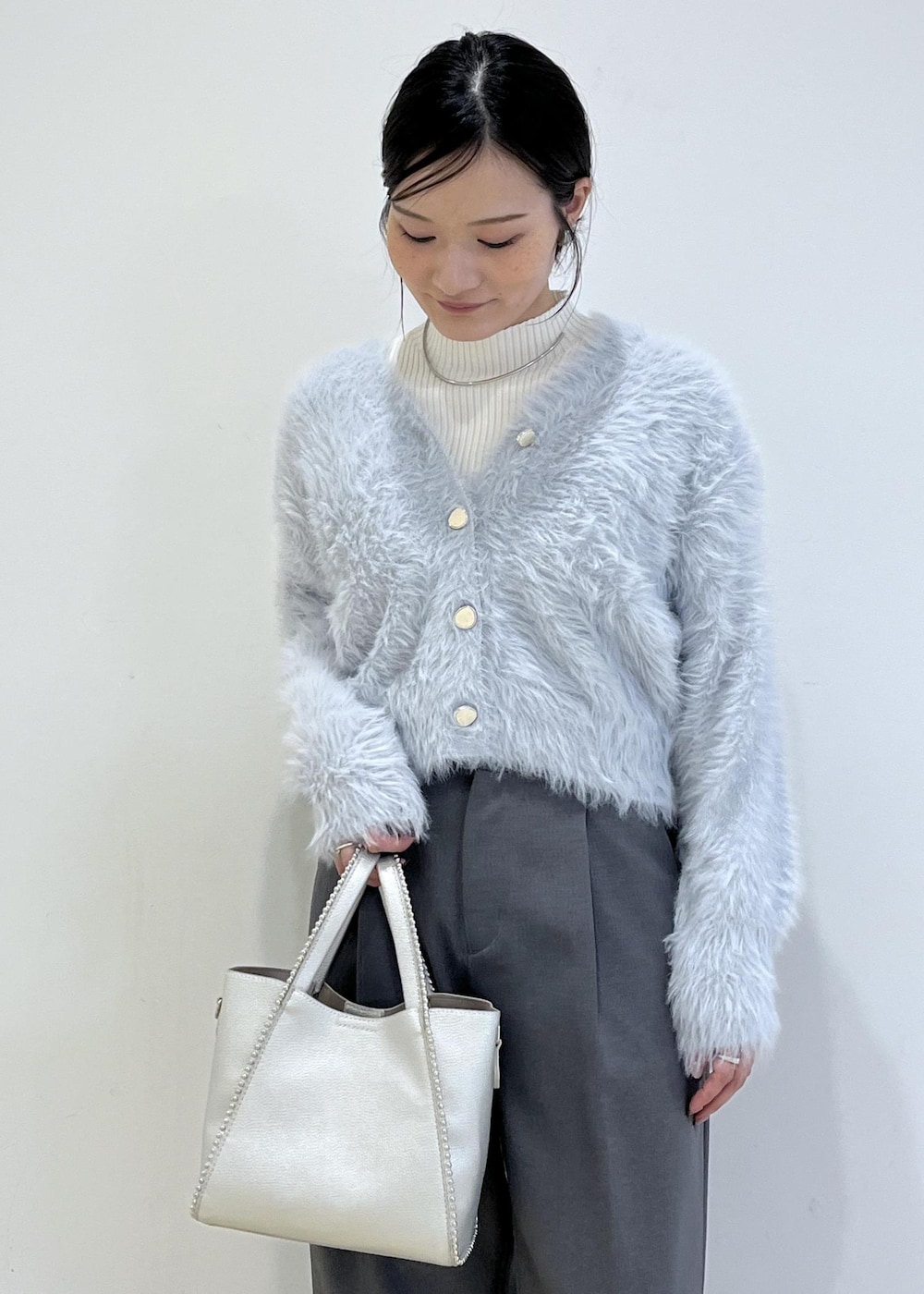 グレー系のスラックス、ホワイト系のパンプス、ブルー系のカーディガン/ボレロを着用したレディースの秋コーディネートの5枚目の写真