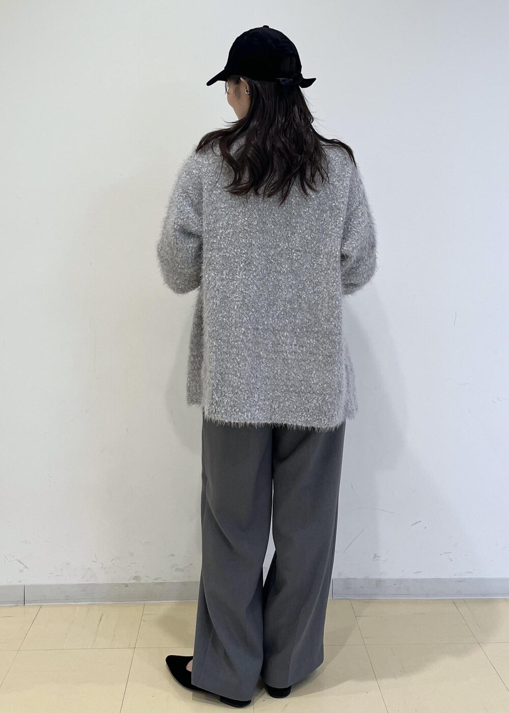 グレー系のスラックス、ブラック系のハンドバッグ、グレー系のカーディガン/ボレロを着用したレディースの秋コーディネートの2枚目の写真