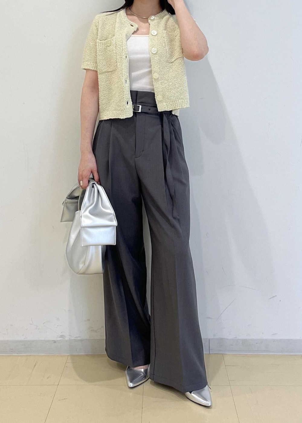 シルバー系のハンドバッグ、シルバー系のパンプス、グリーン系のカーディガン/ボレロを着用したレディースの春コーディネートの2枚目の写真