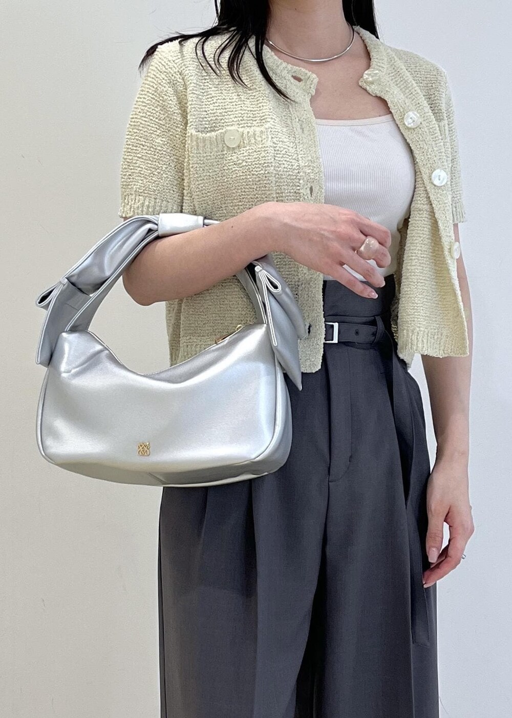 シルバー系のハンドバッグ、シルバー系のパンプス、グリーン系のカーディガン/ボレロを着用したレディースの春コーディネートの7枚目の写真