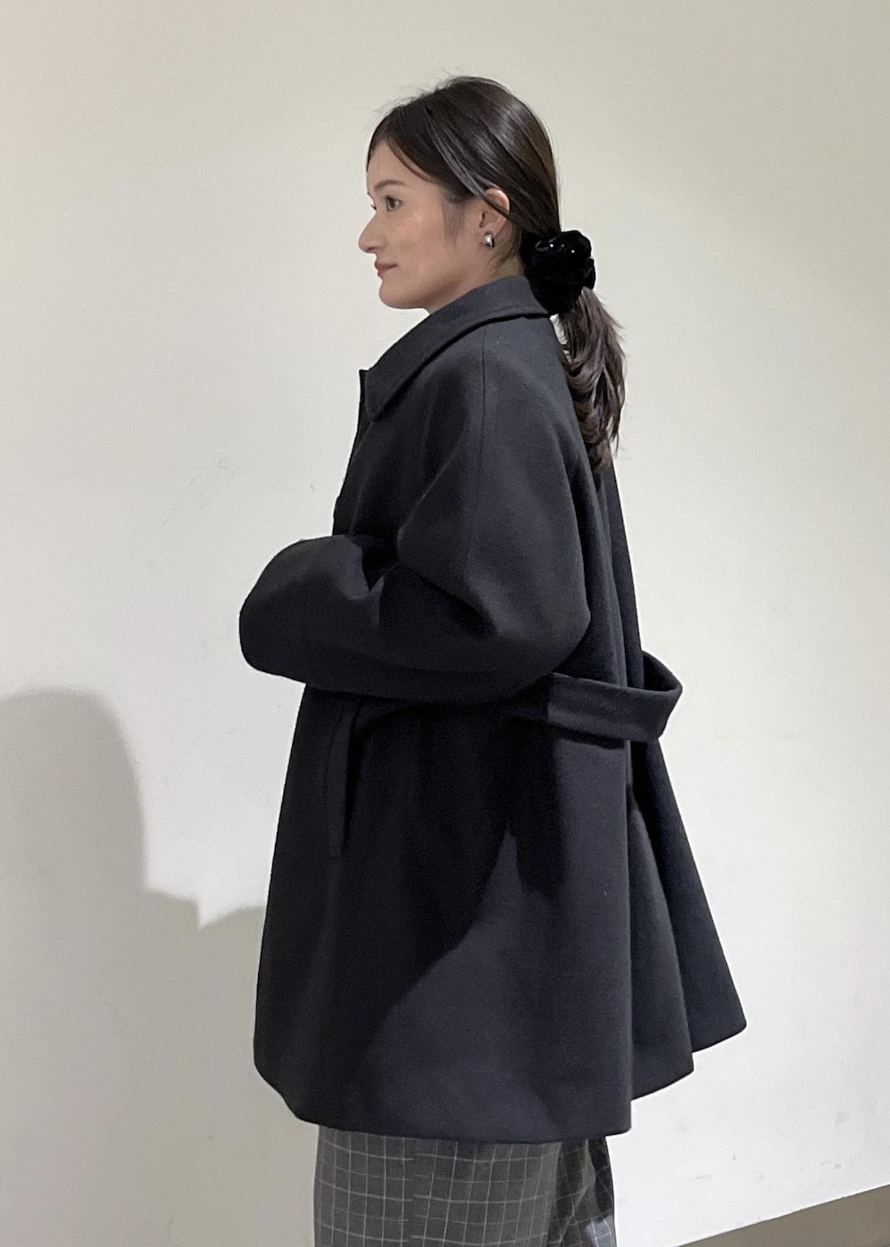 ベージュ系のトートバッグ、ブラック系のテーラードジャケット、ブラック系のチェスターコートを着用したレディースの冬コーディネートの9枚目の写真