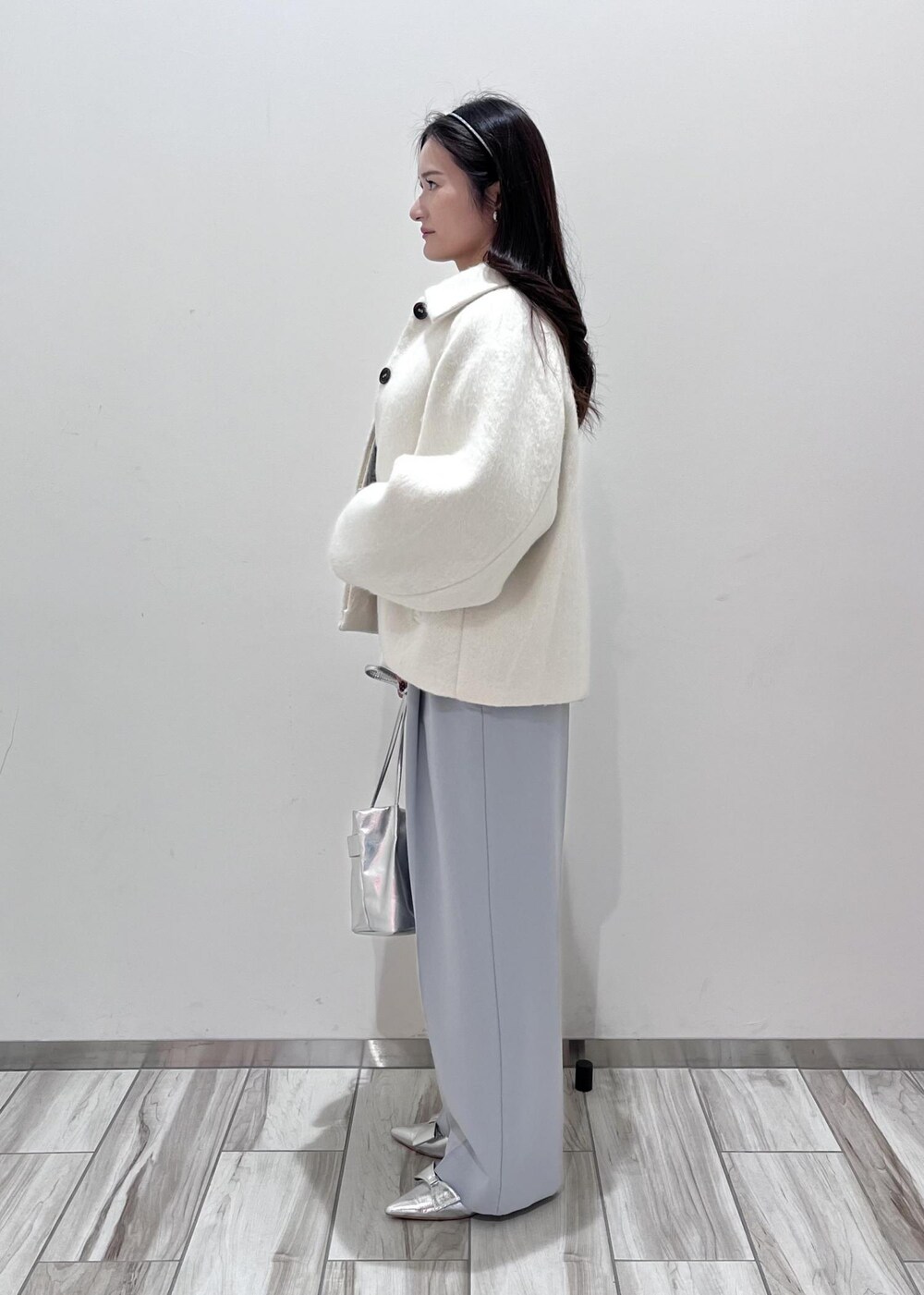 シルバー系のパンプス、シルバー系のショルダーバッグ、ブルー系のスラックスを着用したレディースの秋コーディネートの2枚目の写真