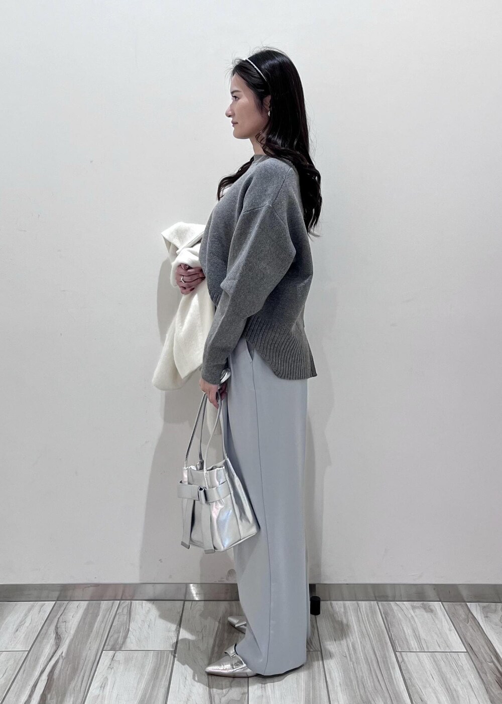 シルバー系のパンプス、シルバー系のショルダーバッグ、ブルー系のスラックスを着用したレディースの秋コーディネートの2枚目の写真