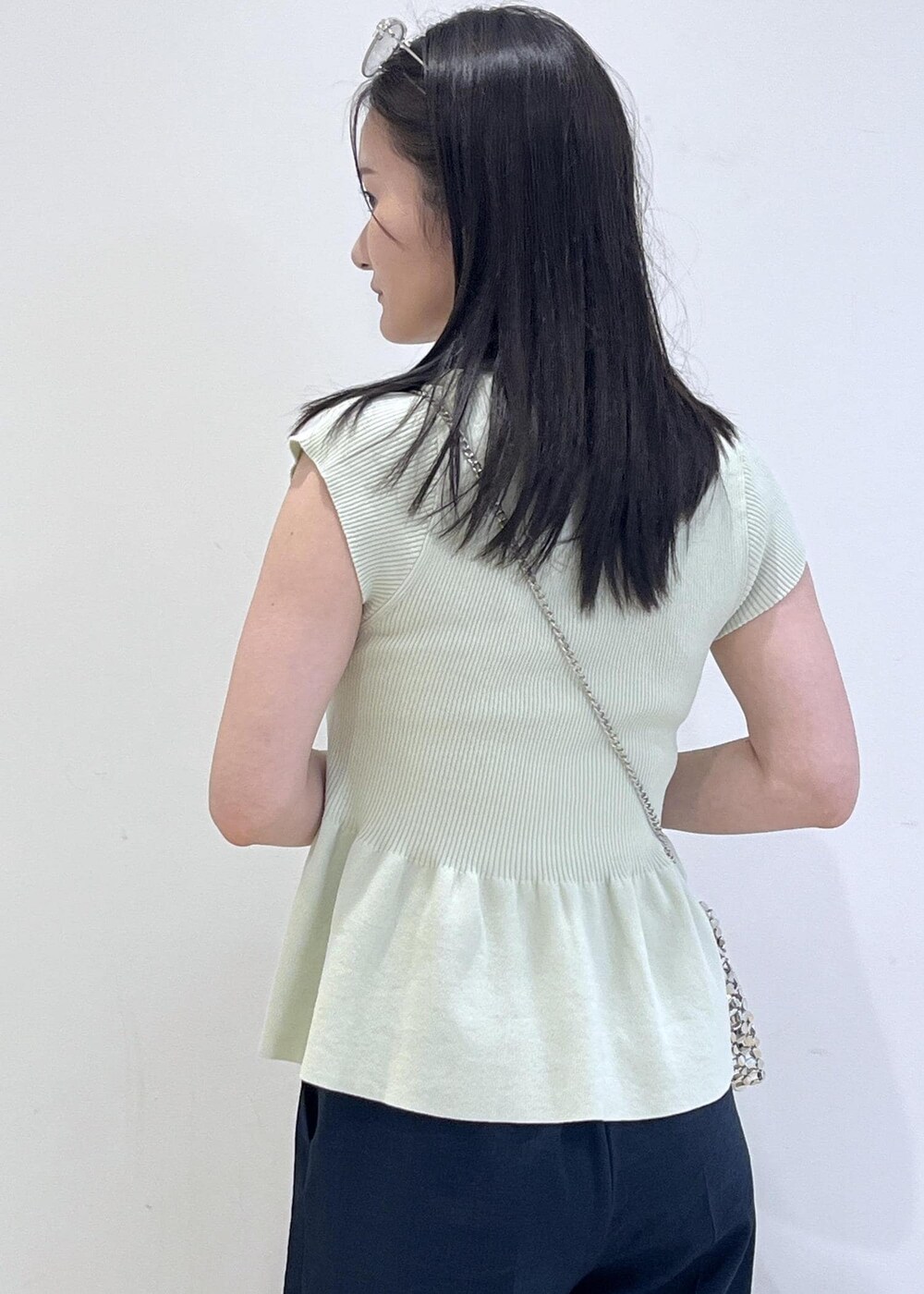 シルバー系のパンプス、シルバー系のハンドバッグ、ブルー系のスラックスを着用したレディースの夏コーディネートの5枚目の写真