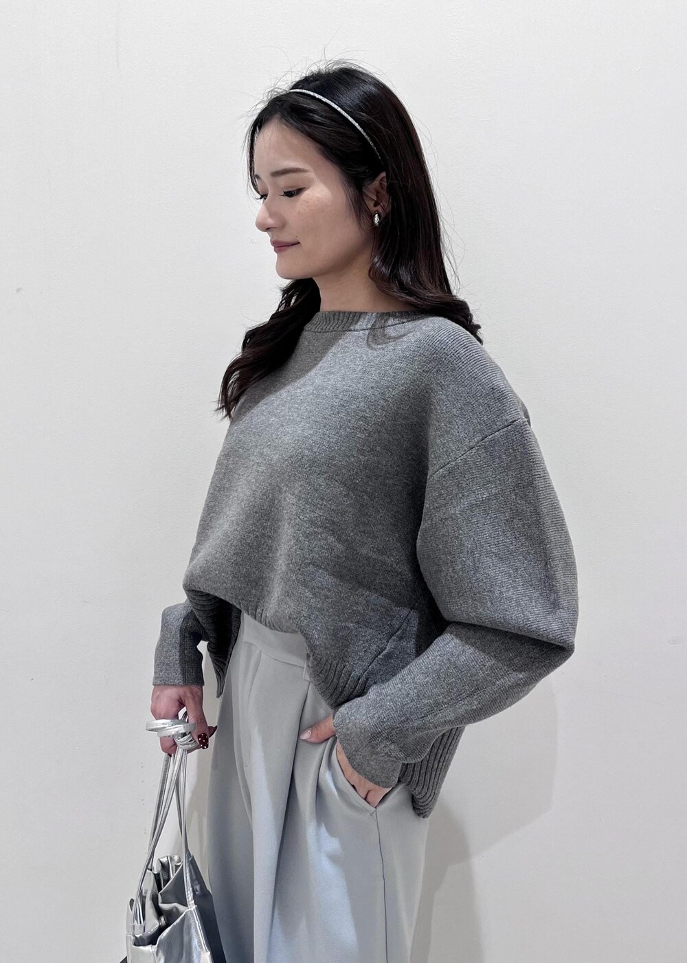 シルバー系のパンプス、シルバー系のショルダーバッグ、ブルー系のスラックスを着用したレディースの秋コーディネートの4枚目の写真