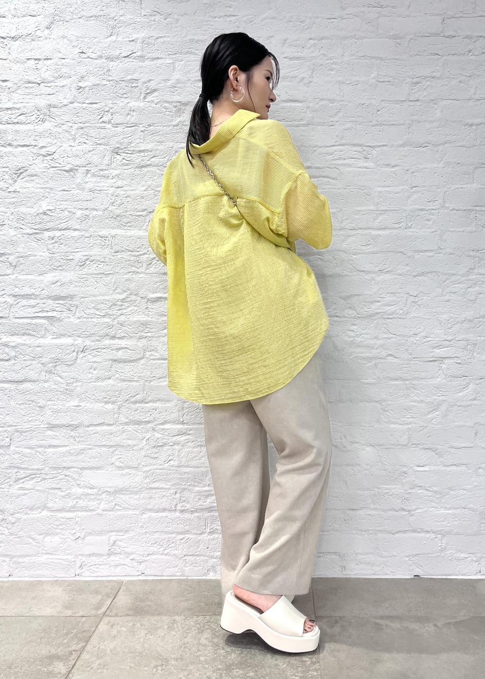 ホワイト系のサンダル、イエロー系のシャツ/ブラウス、ホワイト系のショルダーバッグを着用したレディースの夏コーディネートの2枚目の写真