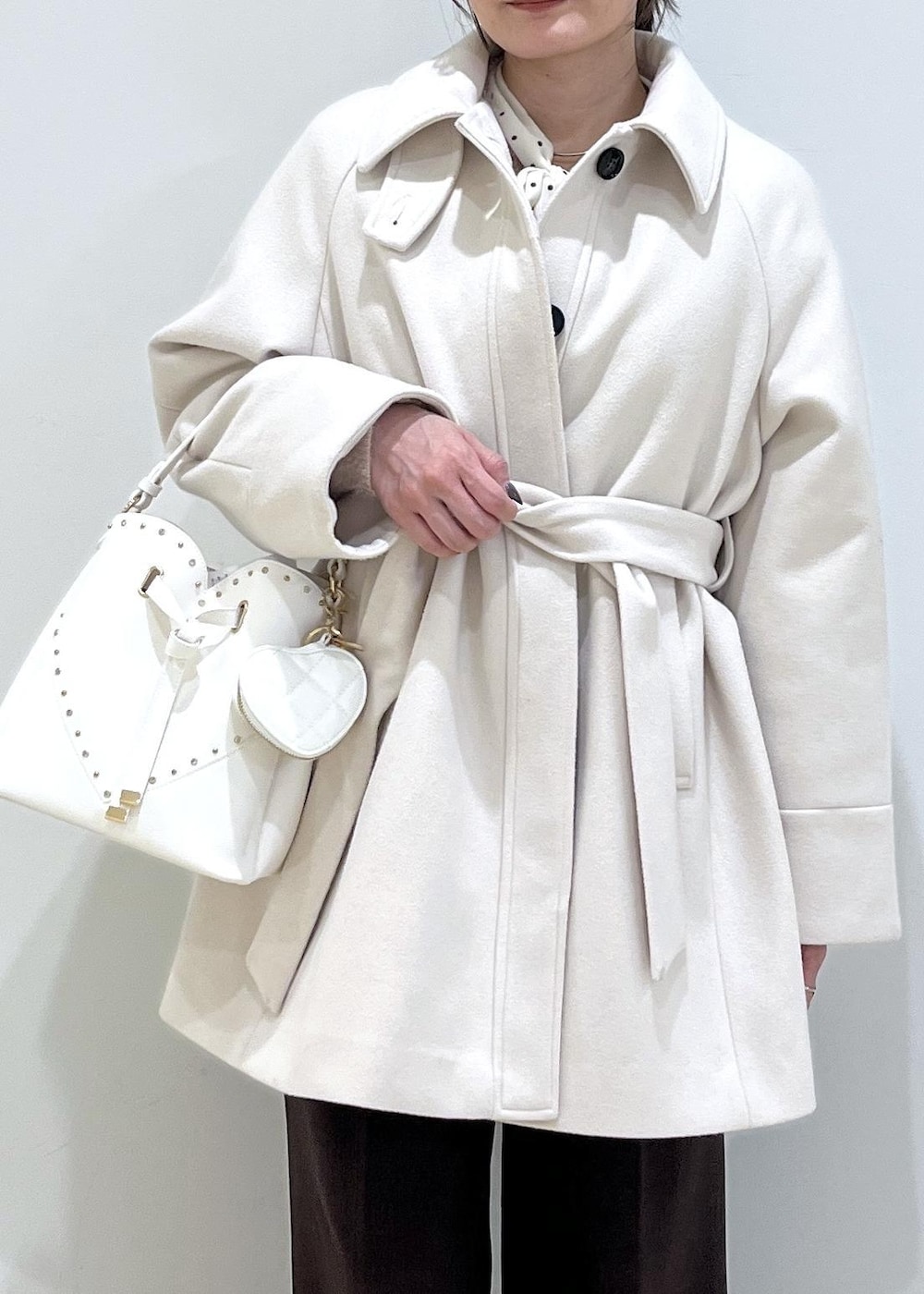 ブラウン系のスラックス、ベージュ系のチェスターコート、ベージュ系のブーツを着用したレディースの冬コーディネートの6枚目の写真