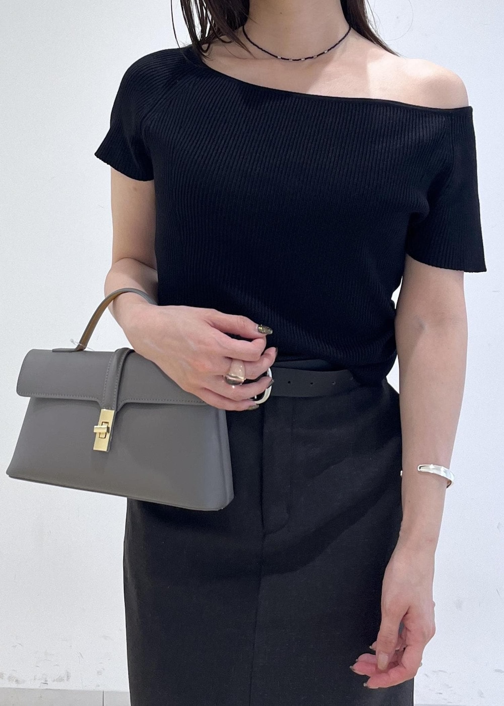 グレー系のショルダーバッグ、グレー系のスカート、ブラック系のニット/セーターを着用したレディースの夏コーディネートの4枚目の写真