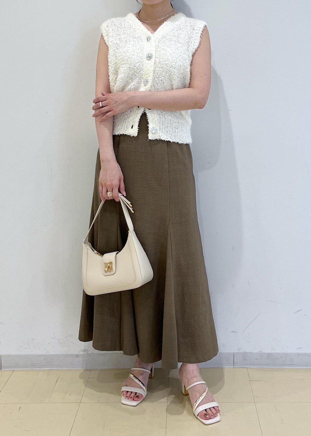 ホワイト系のハンドバッグ、グリーン系のスカート、ホワイト系のサンダルを着用したレディースの春コーディネートの5枚目の写真
