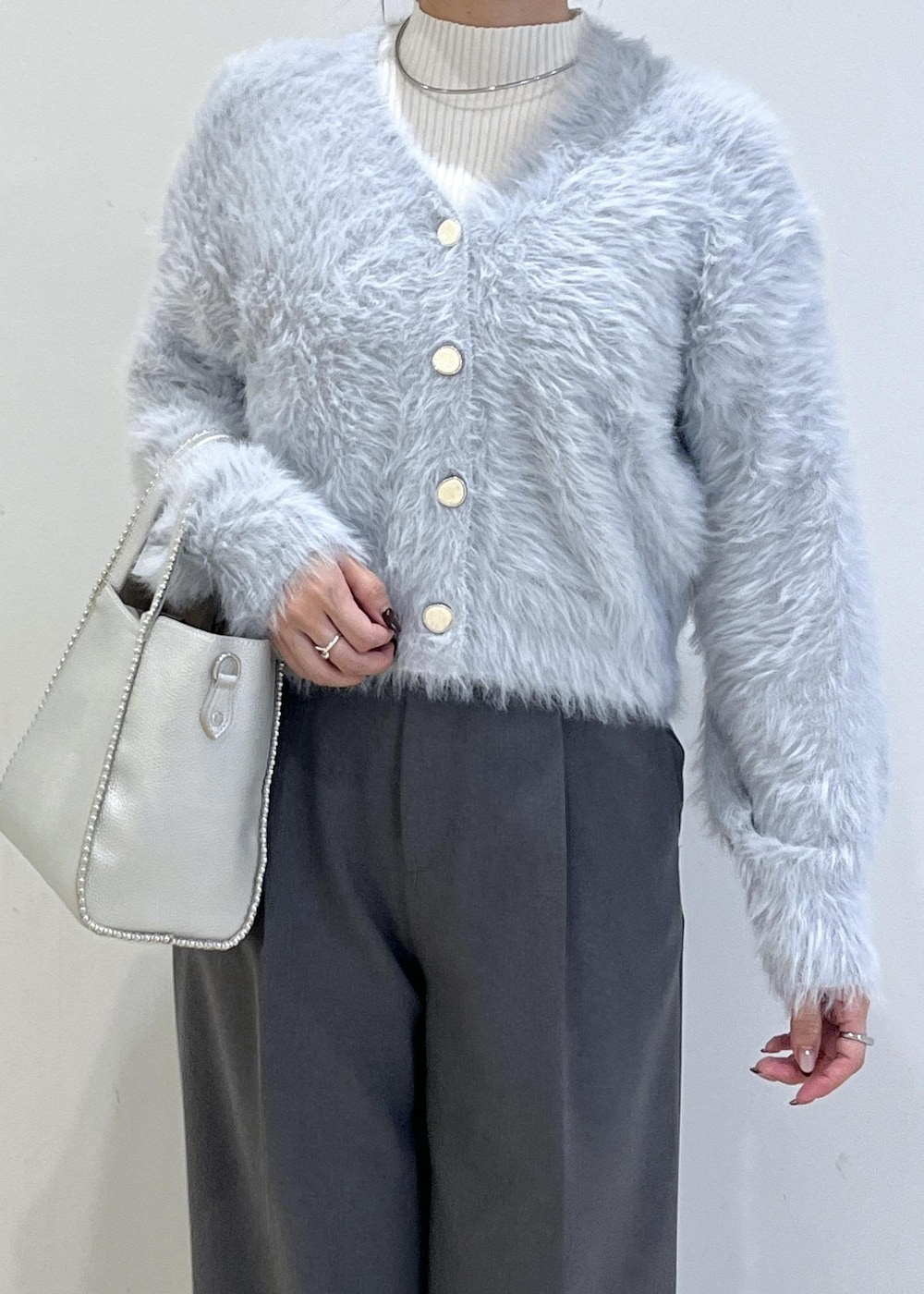 グレー系のスラックス、ホワイト系のパンプス、ブルー系のカーディガン/ボレロを着用したレディースの秋コーディネートの6枚目の写真