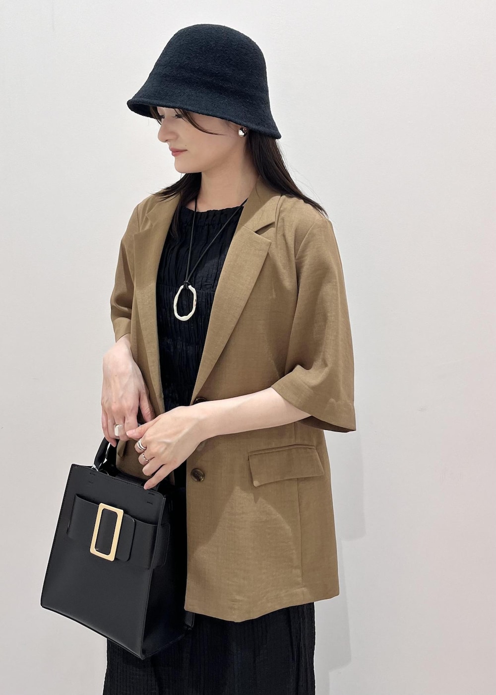 ブラック系のサンダル、ブラック系のハンドバッグ、ブラウン系のテーラードジャケットを着用したレディースの夏コーディネートの2枚目の写真