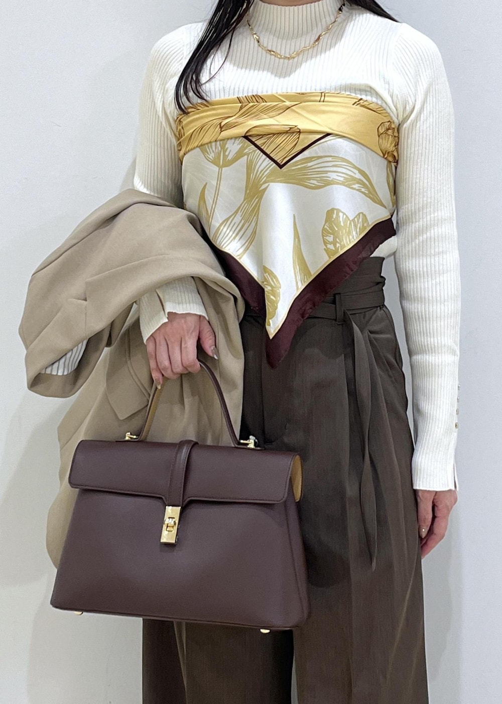 ブラウン系のハンドバッグ、ホワイト系のパンプス、ホワイト系のニット/セーターを着用したレディースの秋コーディネートの3枚目の写真