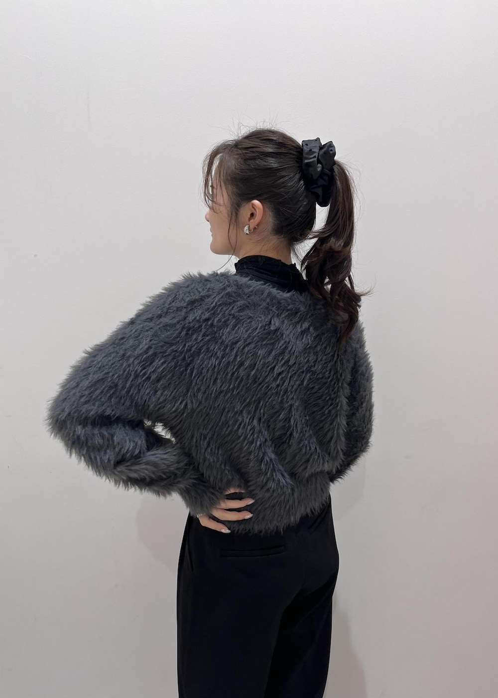 ブラウン系のショルダーバッグ、ブラック系のスラックス、グレー系のカーディガン/ボレロを着用したレディースの冬コーディネートの7枚目の写真