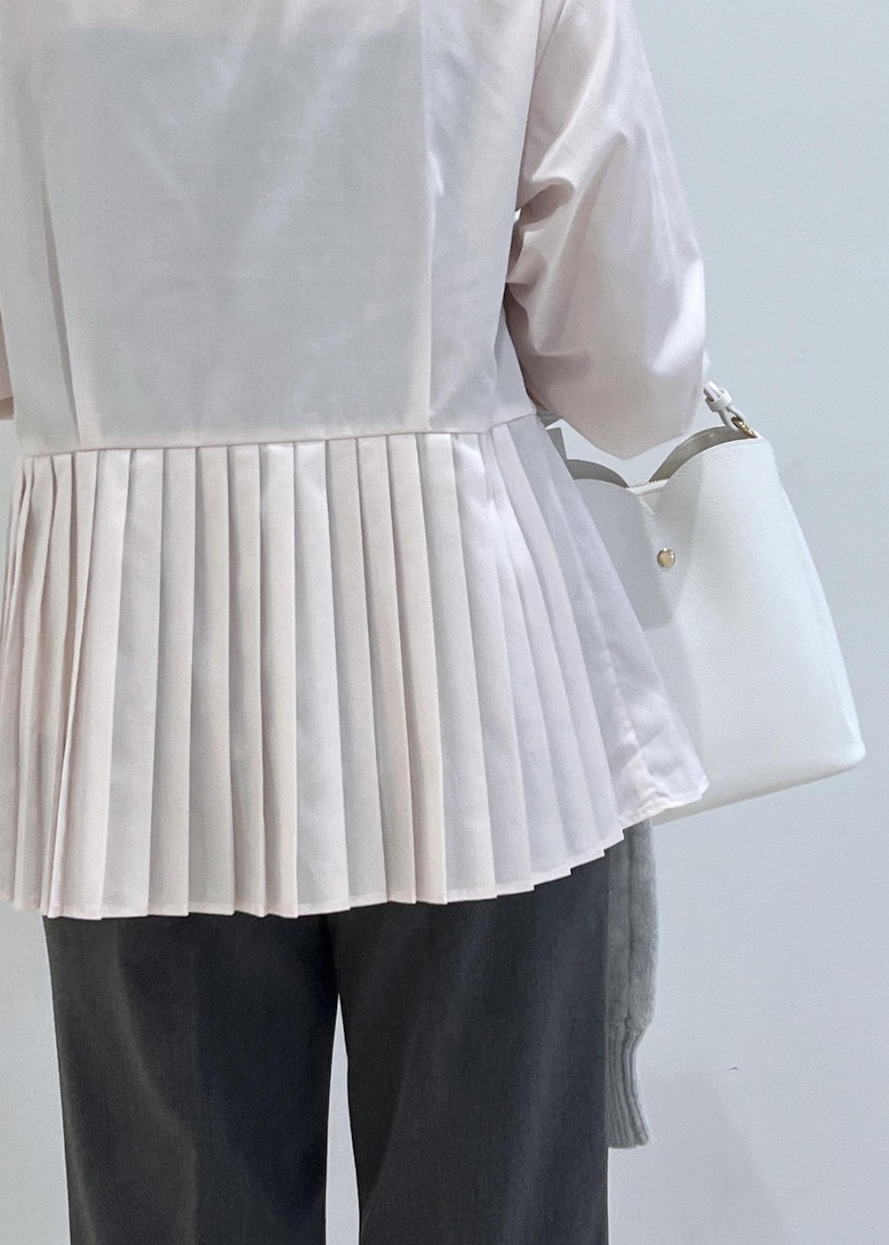 ホワイト系のショルダーバッグ、ホワイト系のパンプス、グレー系のスラックスを着用したレディースの秋コーディネートの7枚目の写真