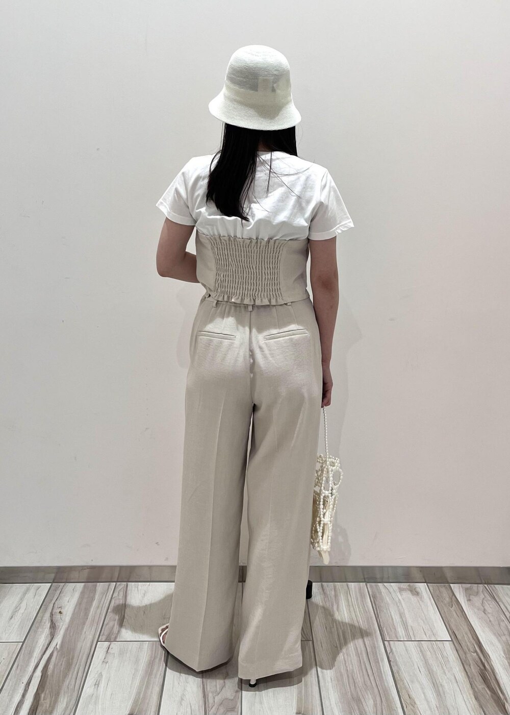 ホワイト系のサンダル、ホワイト系のスラックス、ホワイト系のハンドバッグを着用したレディースの夏コーディネートの5枚目の写真