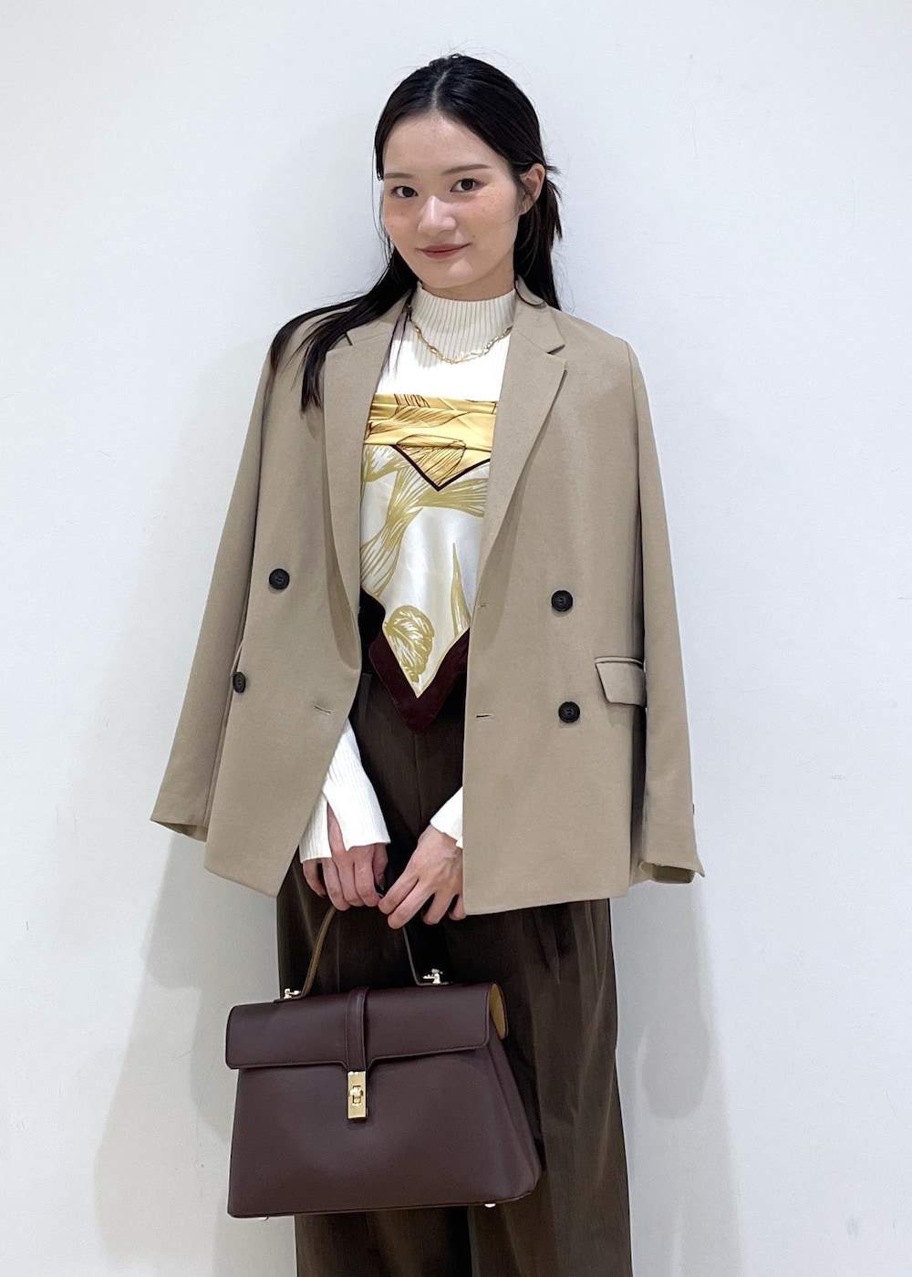 ブラウン系のハンドバッグ、ホワイト系のパンプス、ホワイト系のニット/セーターを着用したレディースの秋コーディネートの2枚目の写真