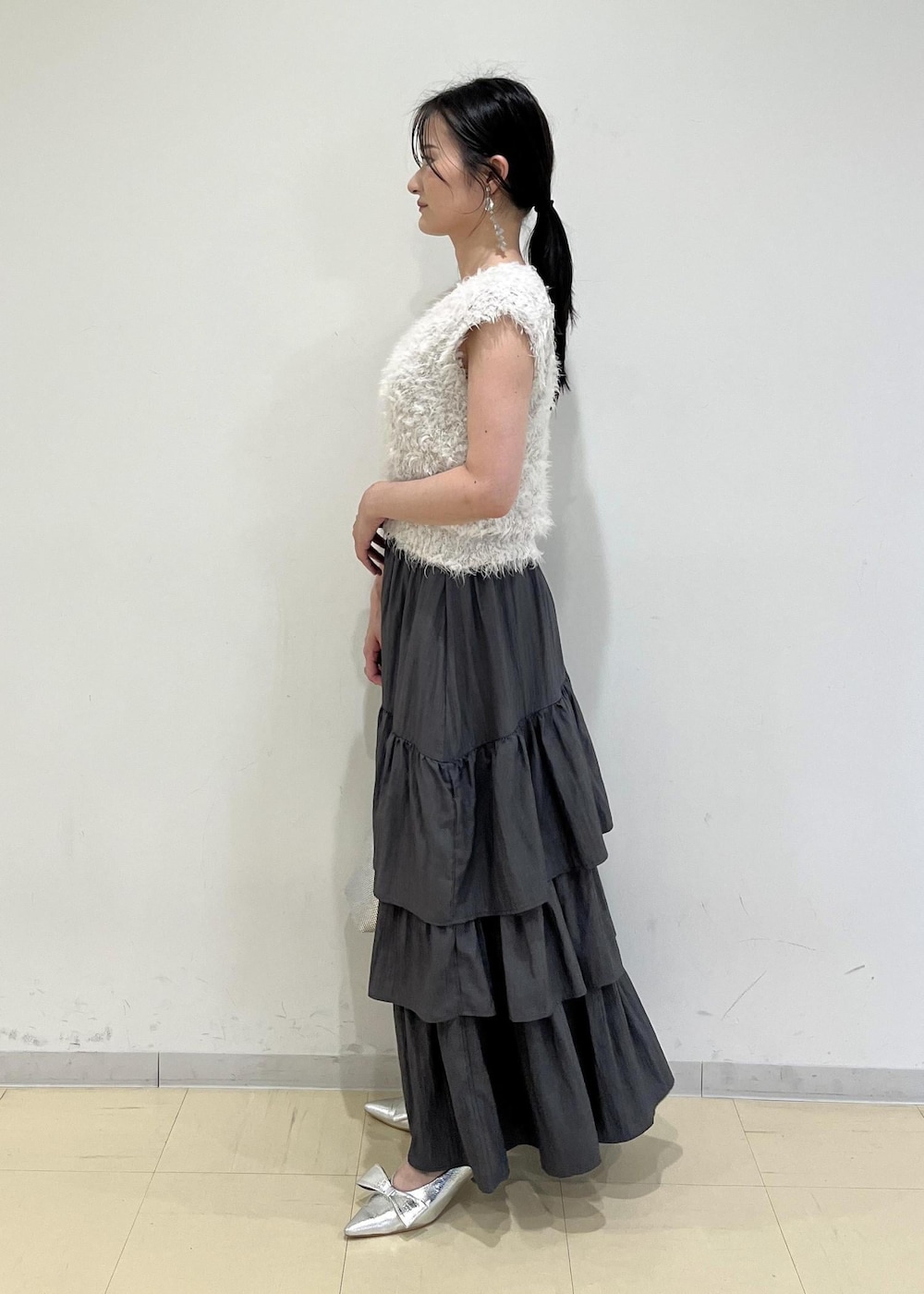 シルバー系のパンプス、シルバー系のショルダーバッグ、グレー系のスカートを着用したレディースの夏コーディネートの2枚目の写真