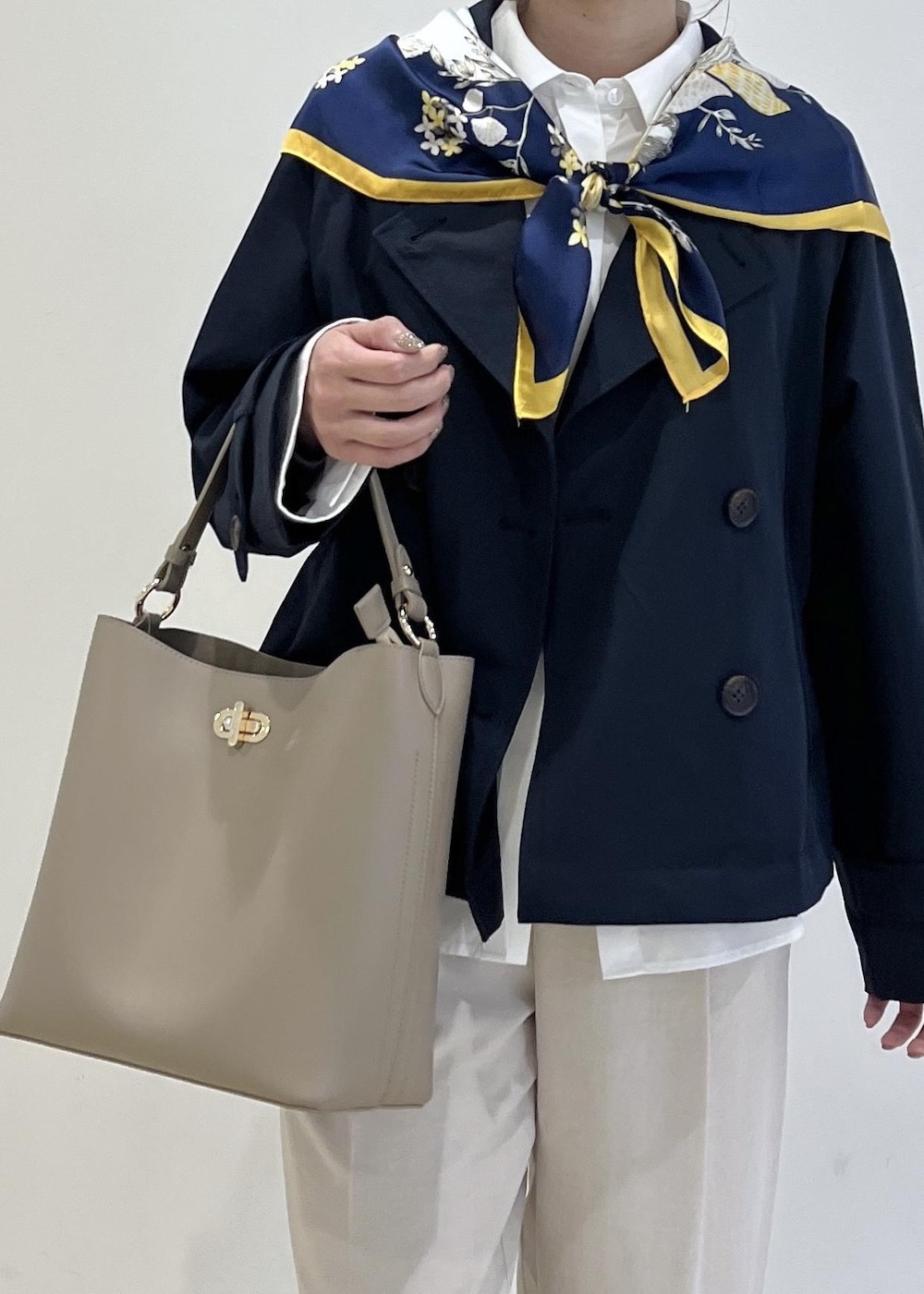 ブラック系のパンプス、ベージュ系のショルダーバッグ、ブルー系のトレンチコートを着用したレディースの春コーディネートの4枚目の写真