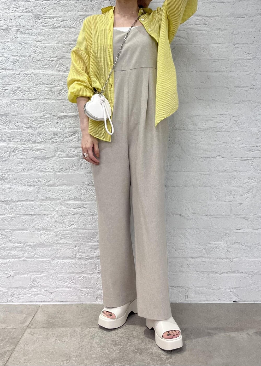 ホワイト系のサンダル、イエロー系のシャツ/ブラウス、ホワイト系のショルダーバッグを着用したレディースの夏コーディネートの3枚目の写真