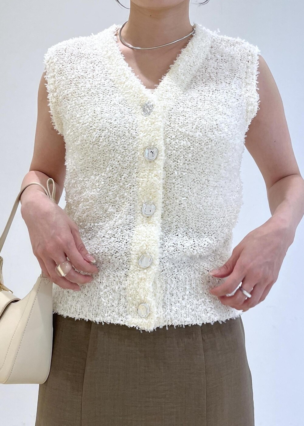 ホワイト系のハンドバッグ、グリーン系のスカート、ホワイト系のサンダルを着用したレディースの春コーディネートの8枚目の写真